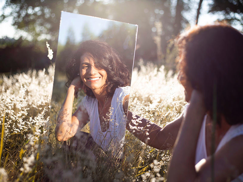 A young woman looks into a mirror