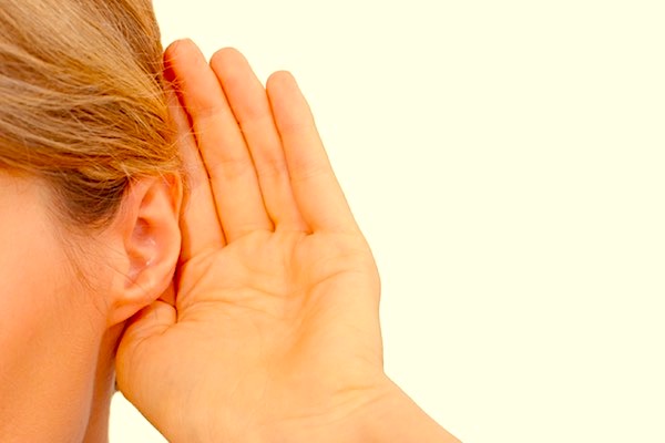 A woman's hand cupped next to her ear in a way that might help her hear better