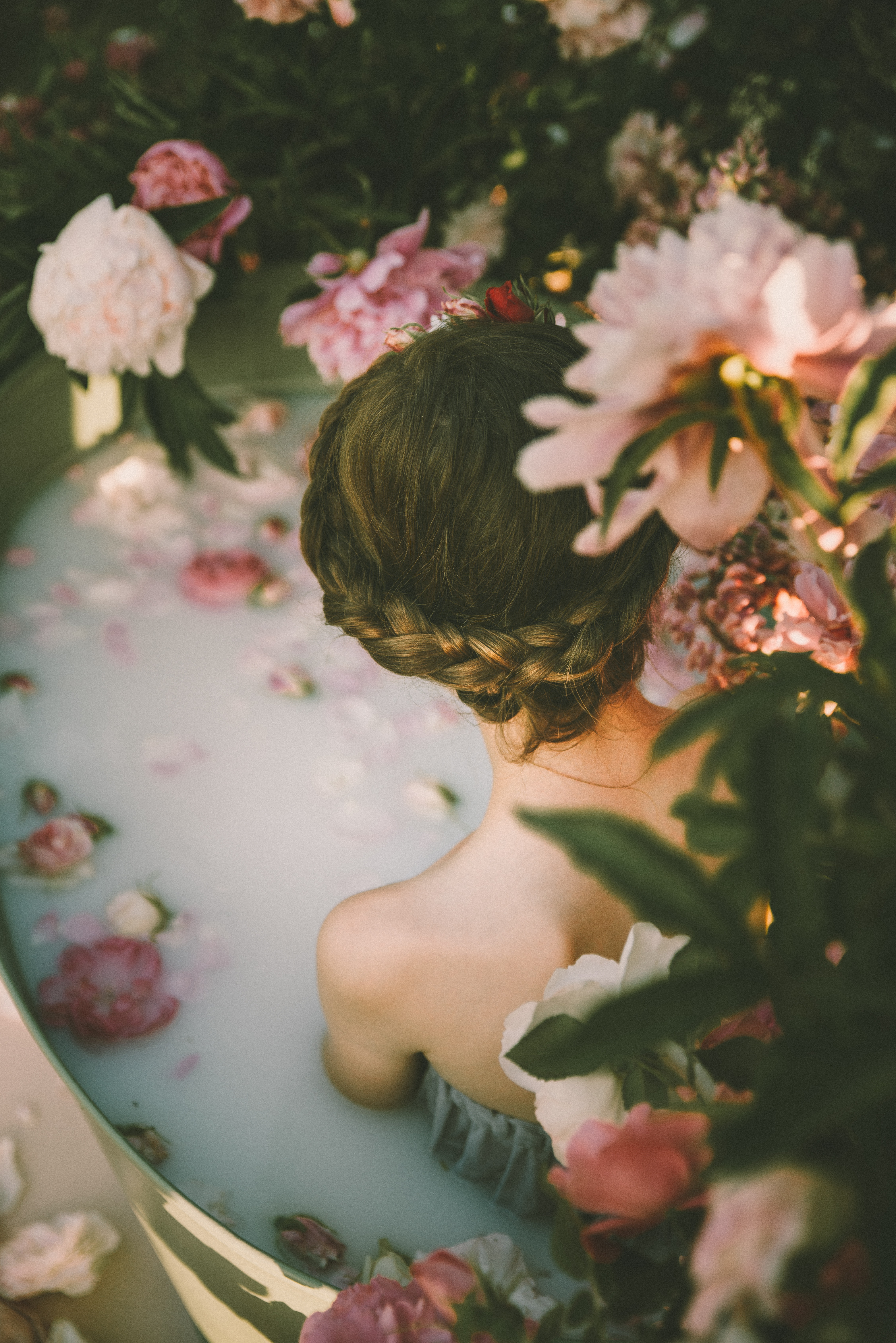 A woman sitting in a bath of flowers