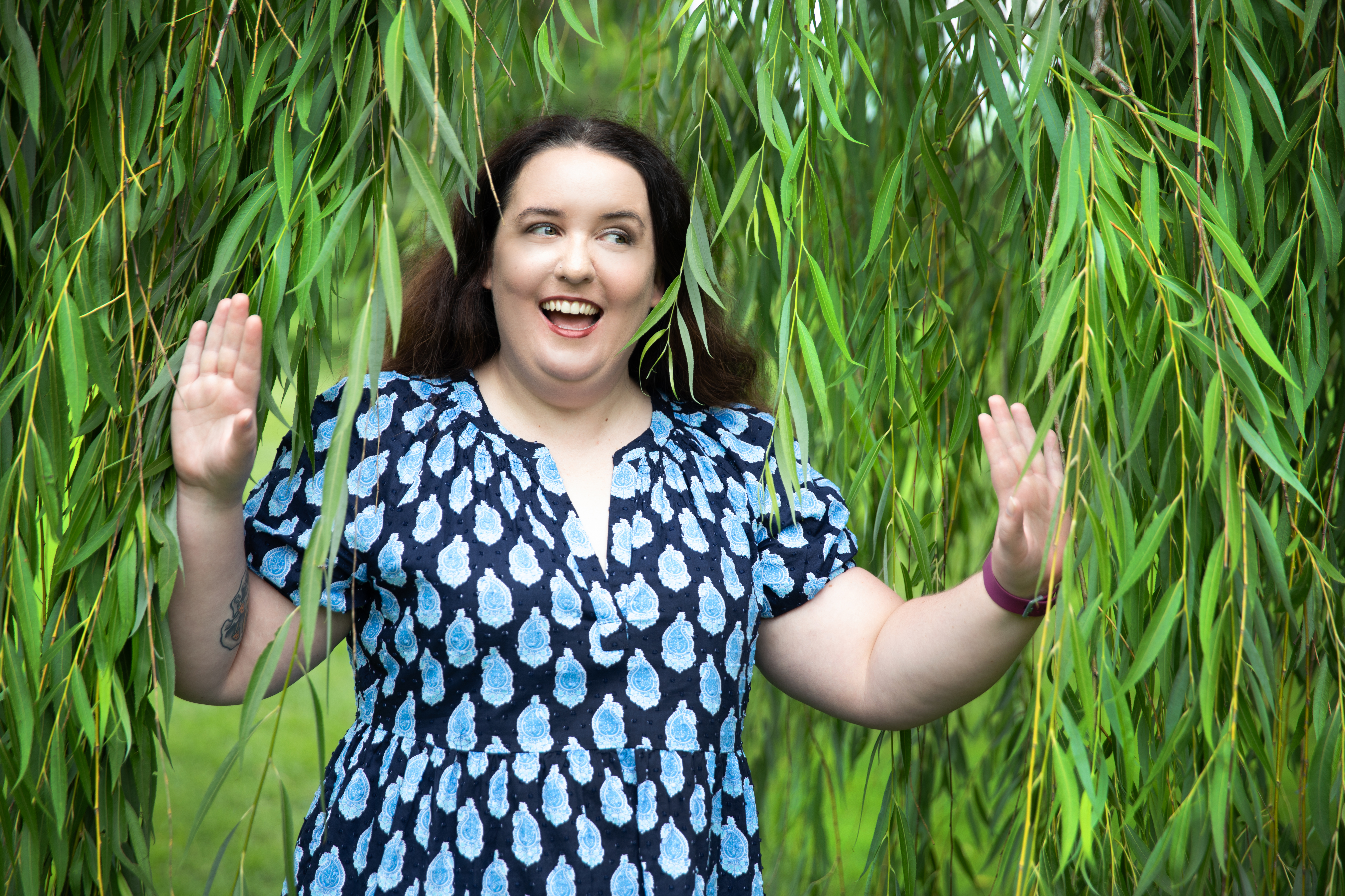 Regan pushing apart the branches of a willow tree and smiling