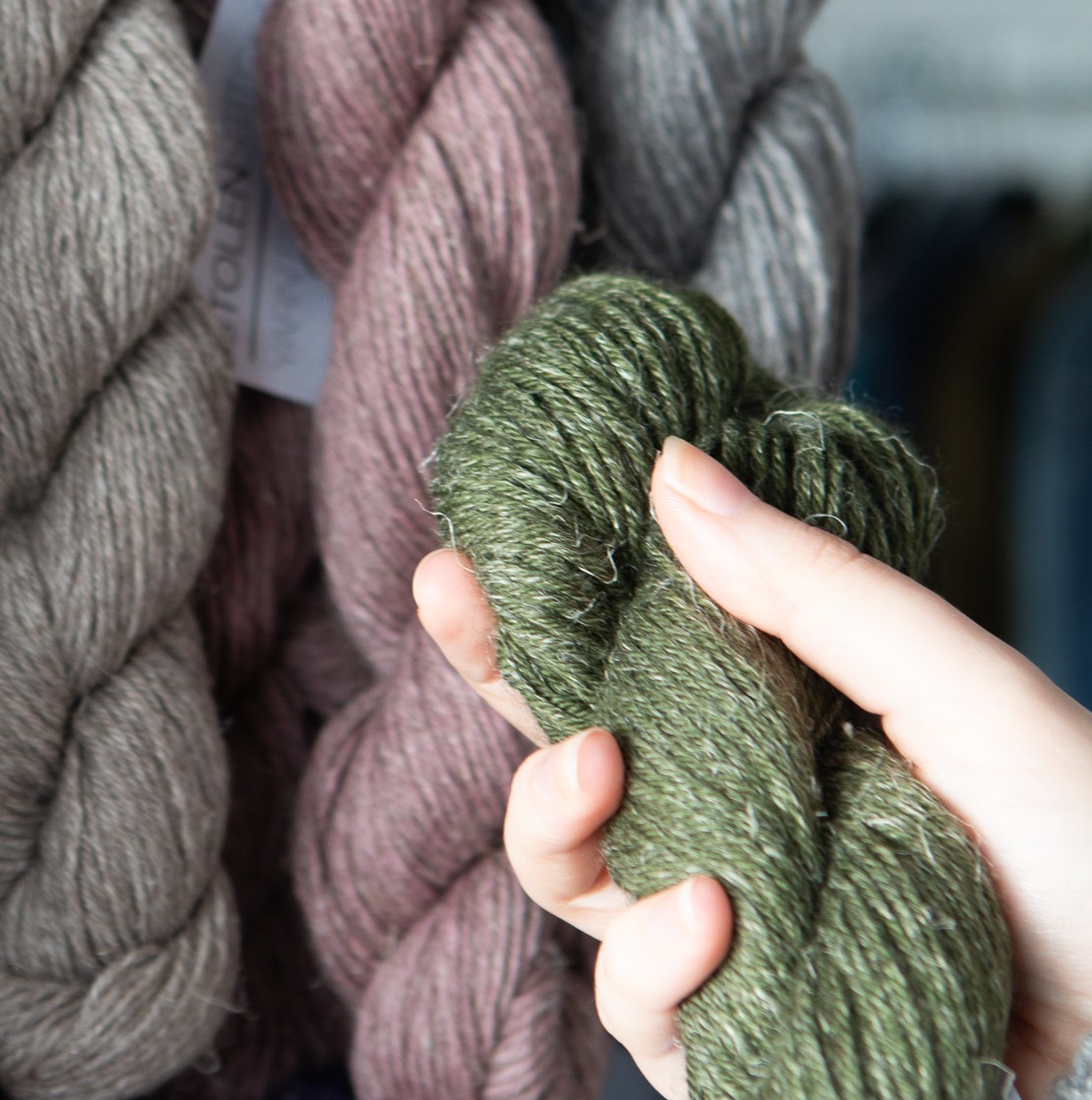 Hand holding a yarn up to another to choose colourway.