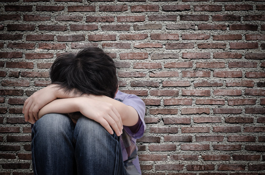 little boy holding his head and looking sad