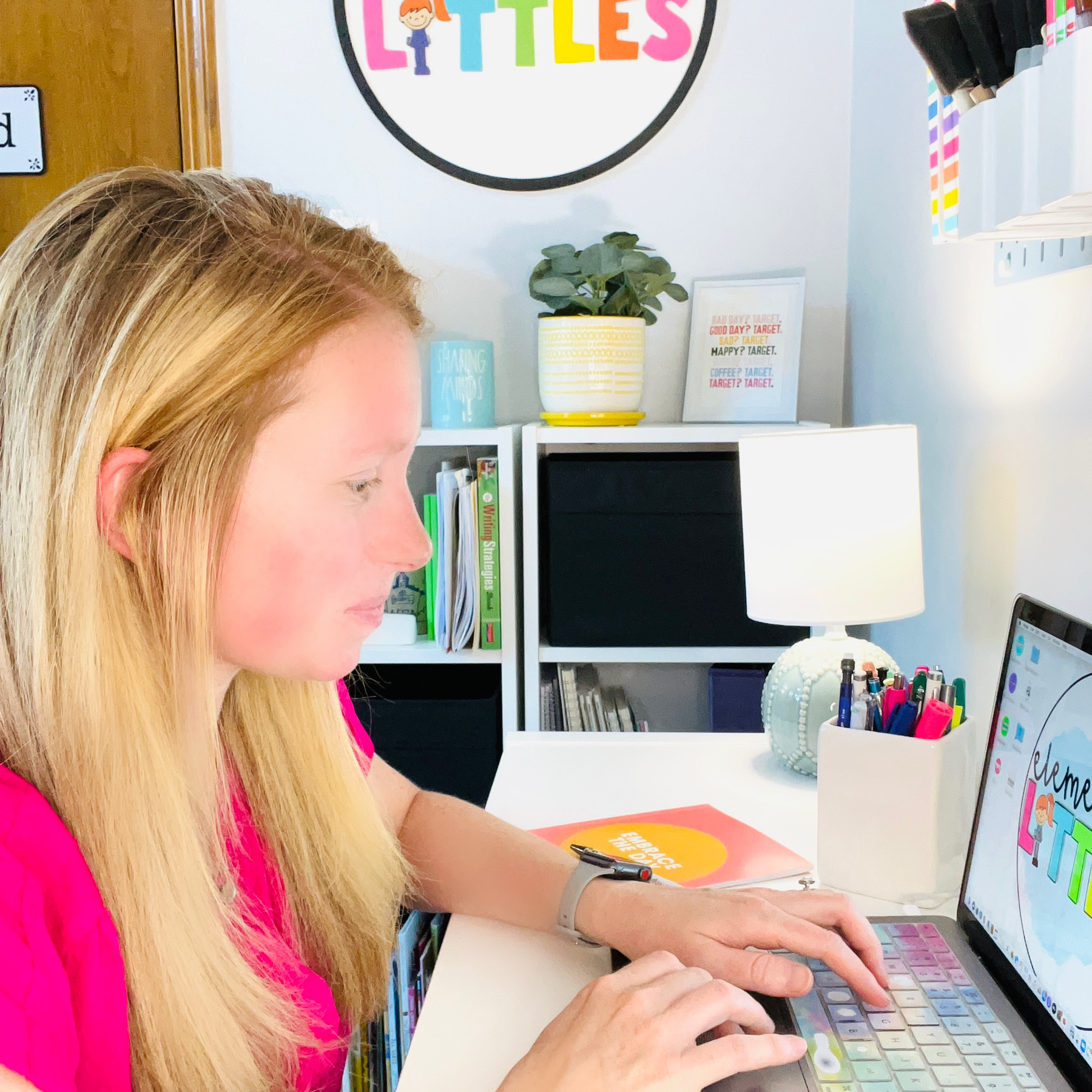 Girl looking at her computer with a smile on her face and her on the computer like she&#39;s typing. She is sitting at a desk.