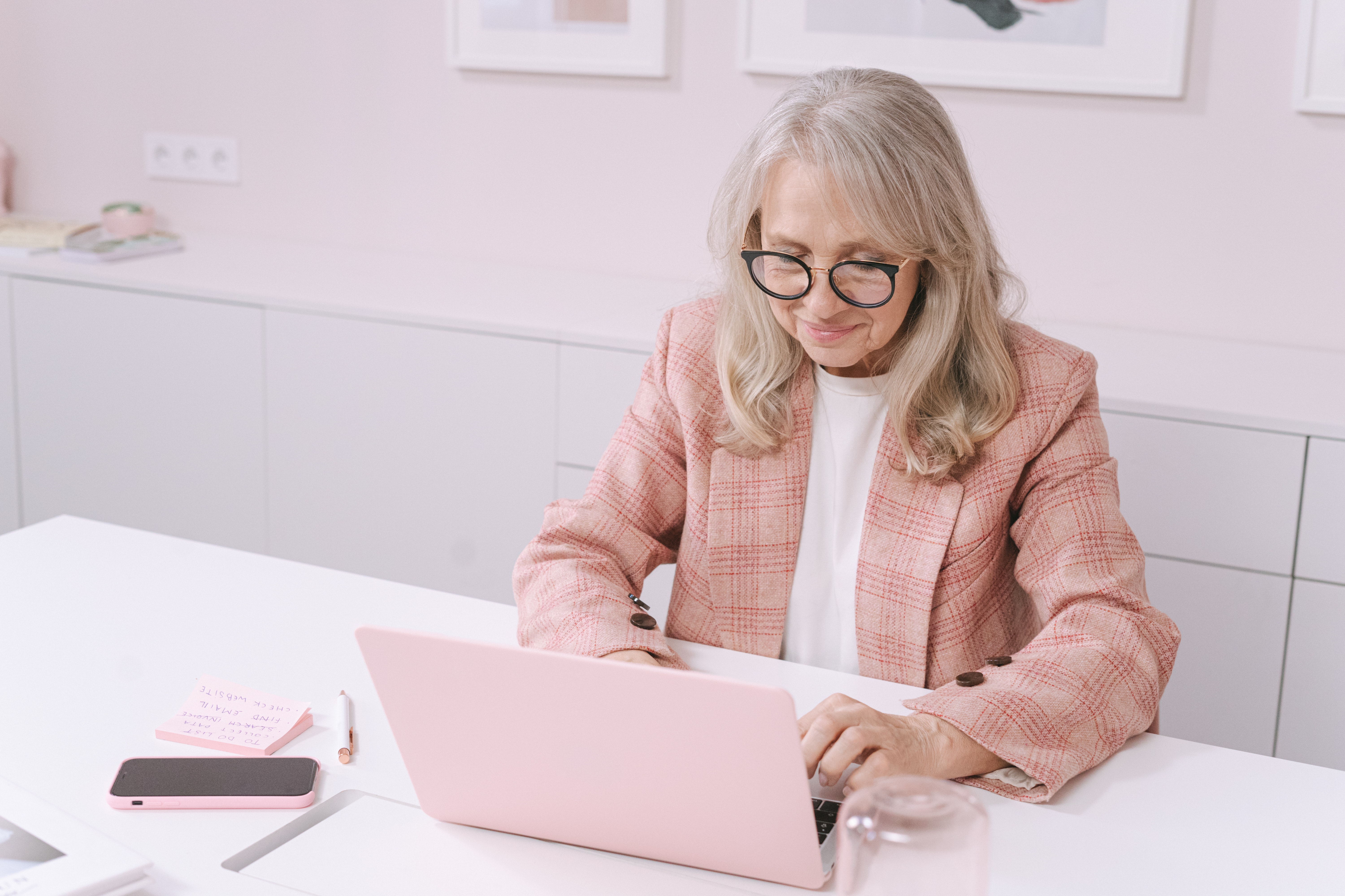 woman sitting at desk with pink laptop