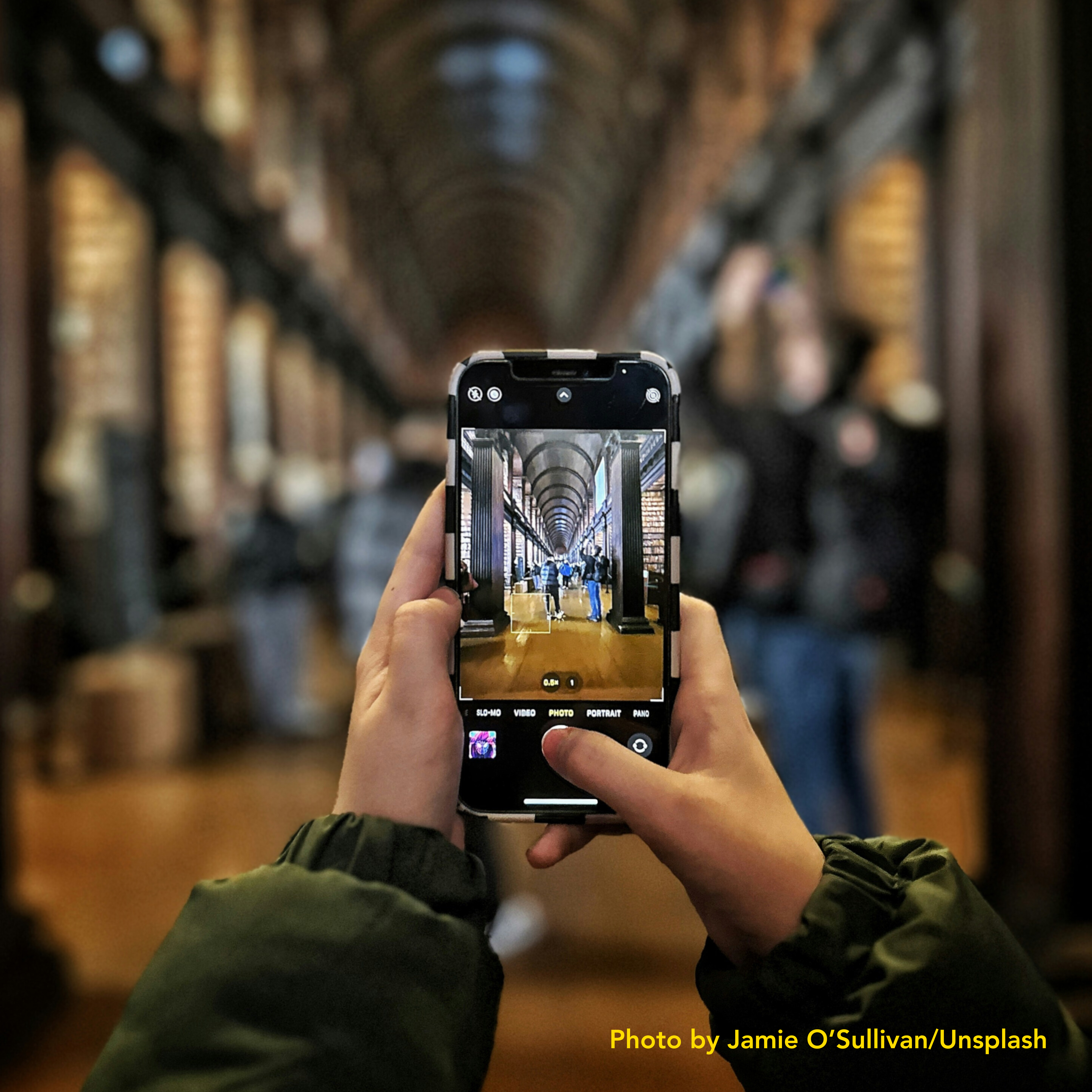 Hands holding phone device to take a photo of a cathedral-like library