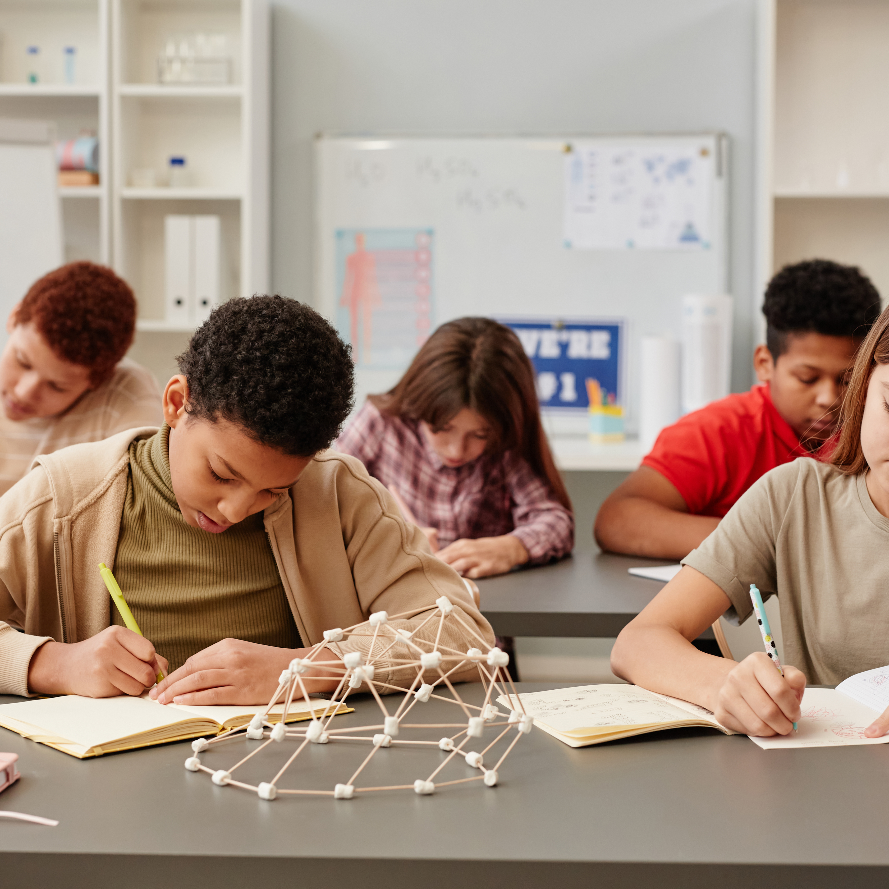 students writing in notebook with toothpick and marshmallow structure