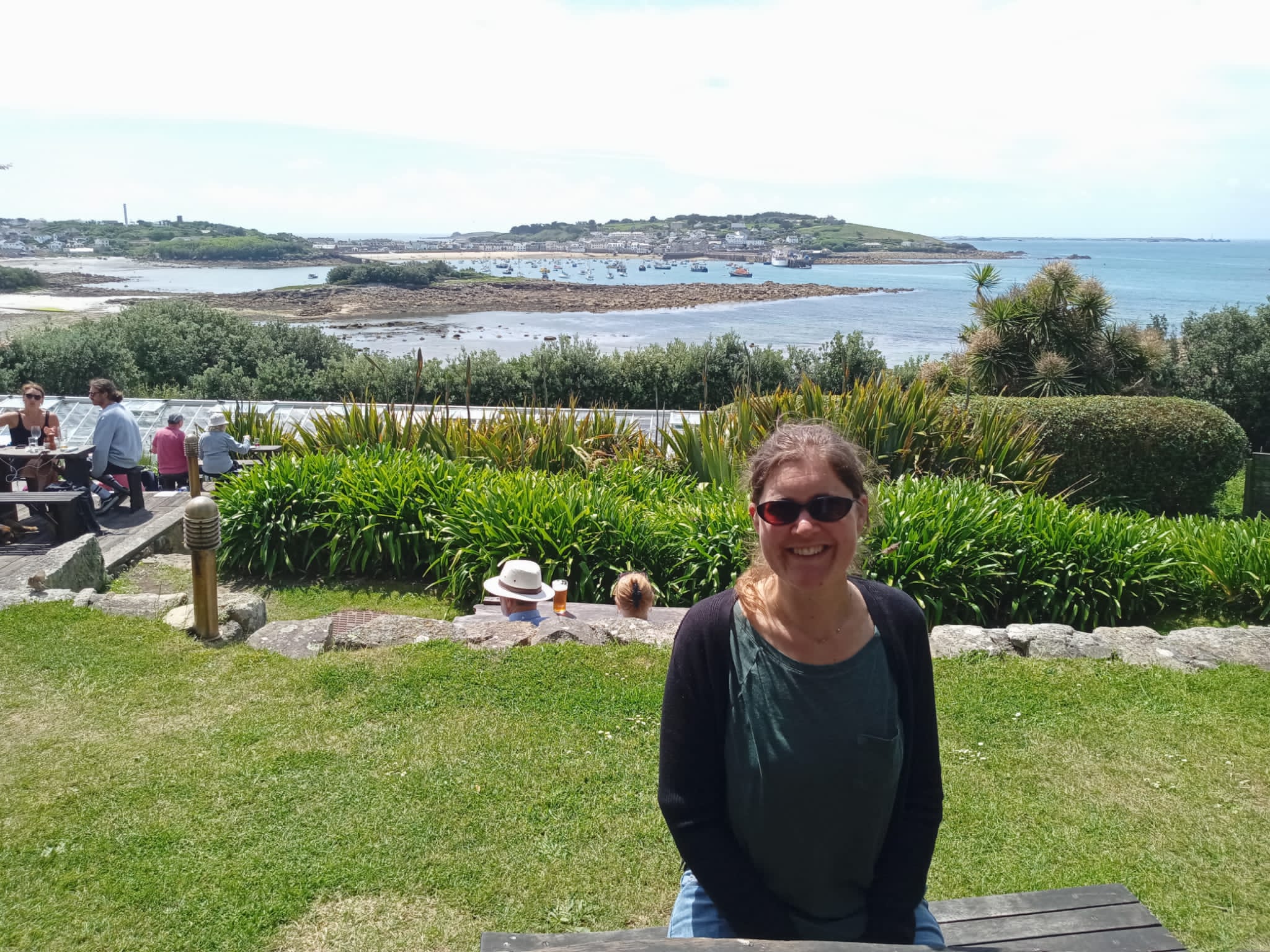 english language coach for non-native teachers of English sitting in the sunshine with views of the Scilly Isles behind her