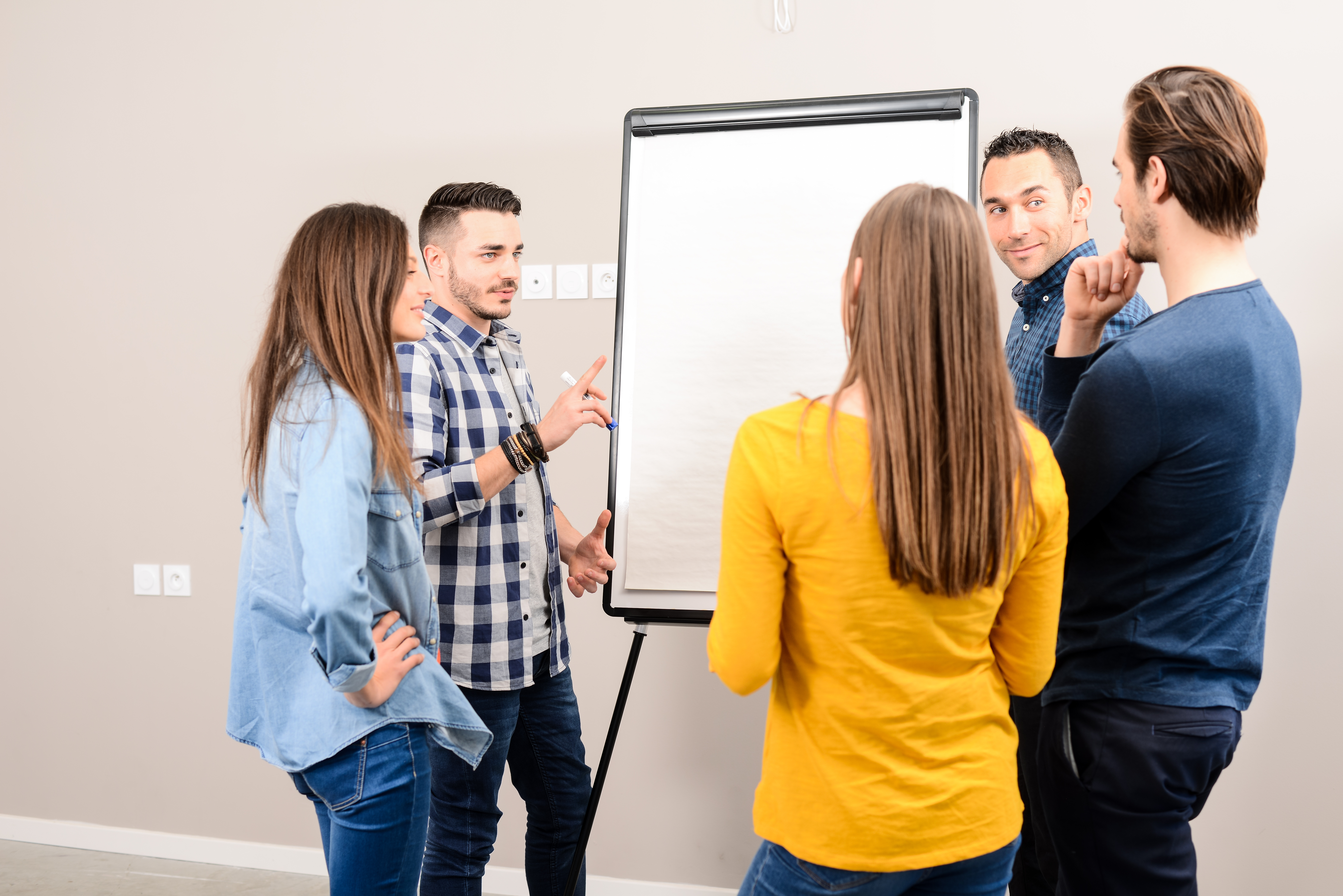 A group of people standing around a white board working together 