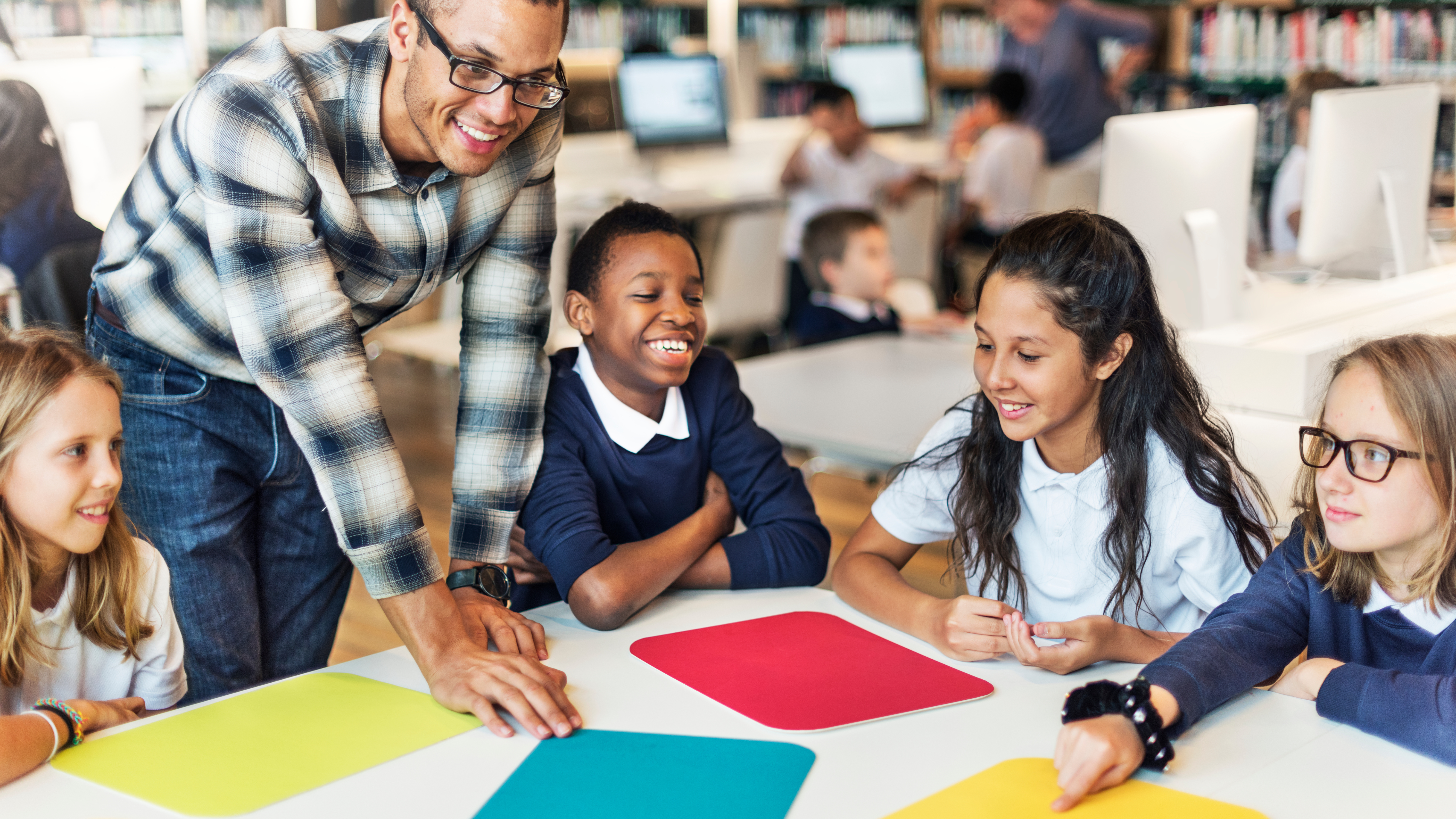 teacher standing alongside table working with students