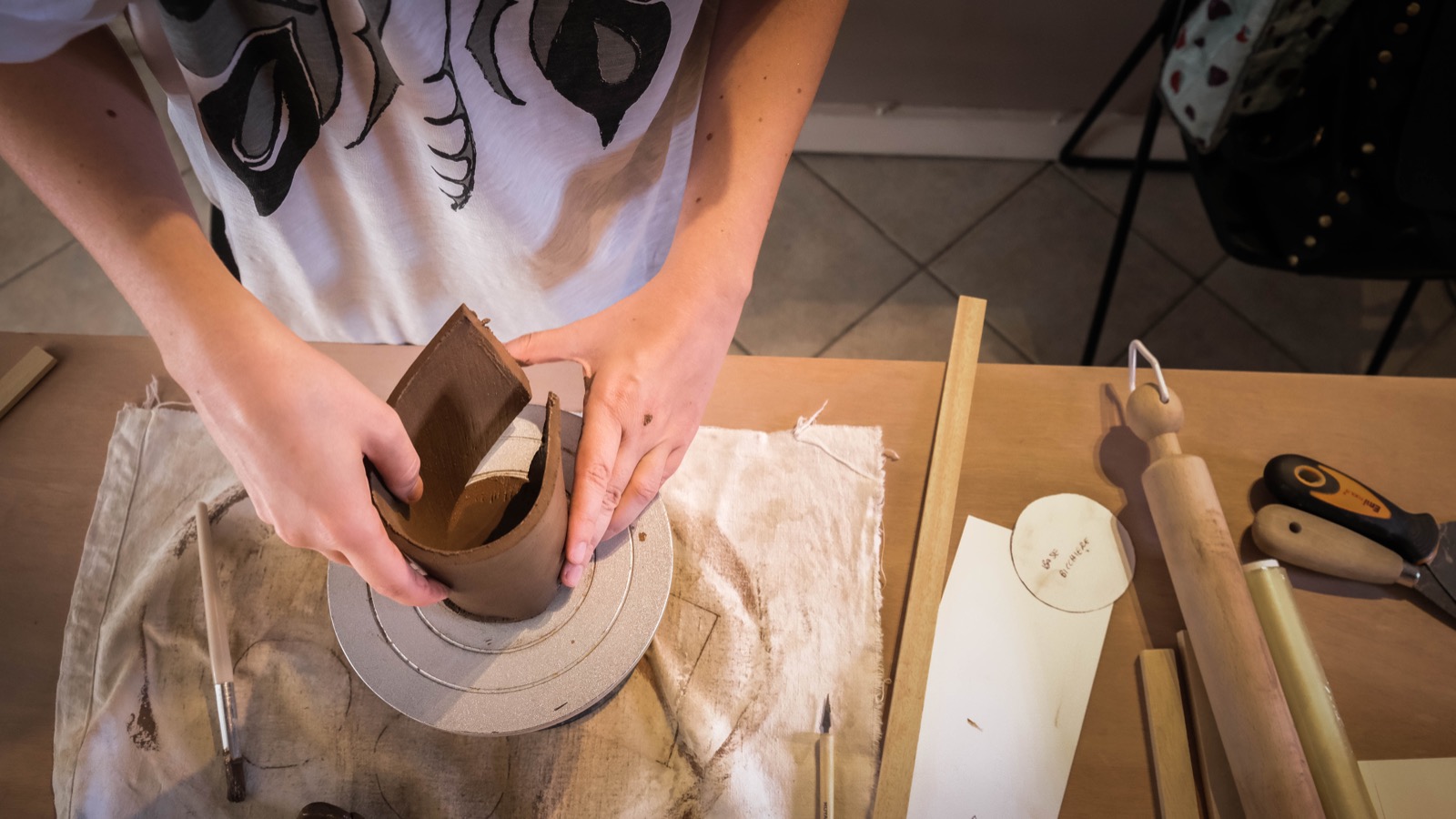Mani che realizzano un bicchiere in ceramica usando argilla scura