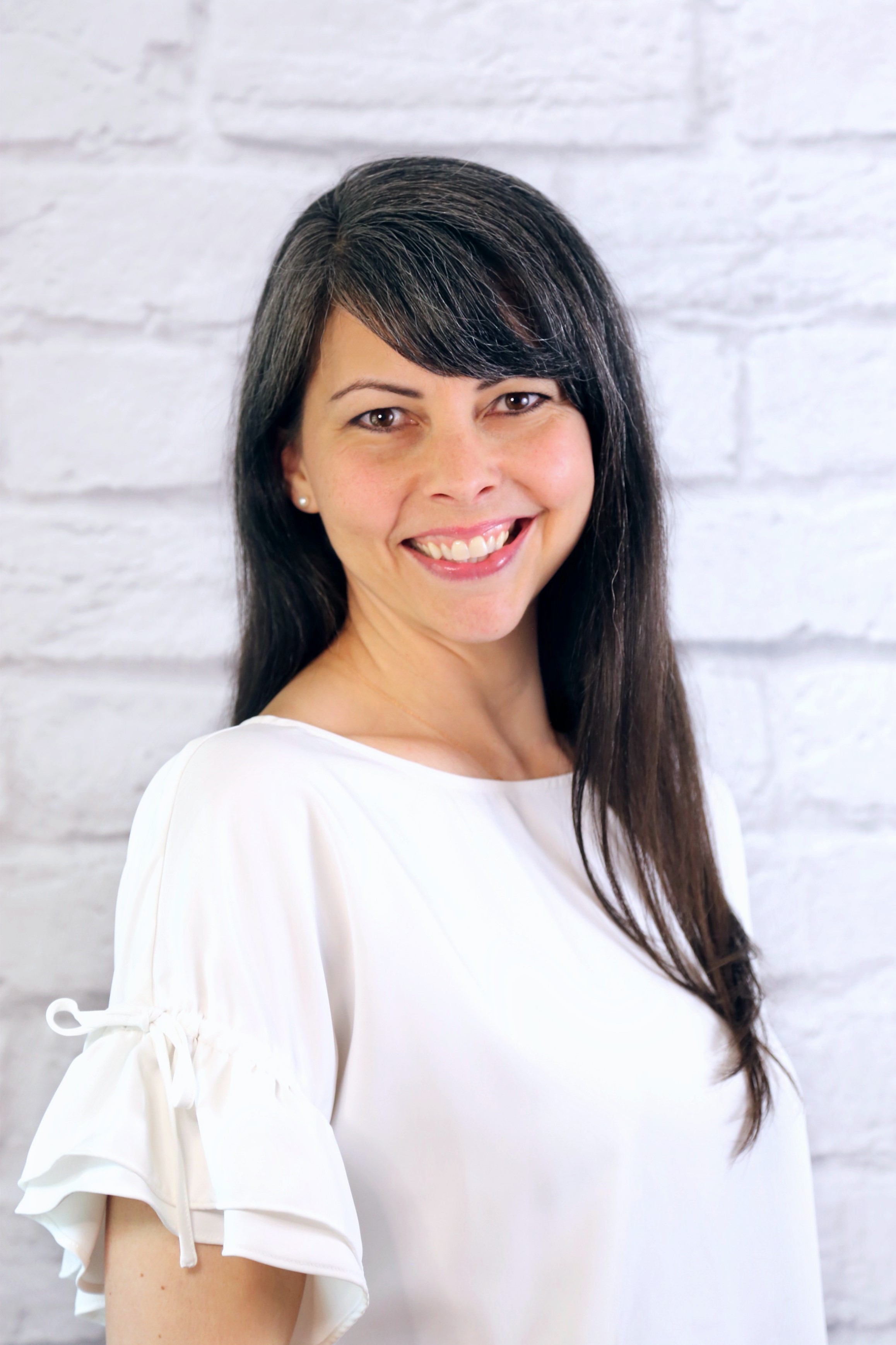 Head shot of Dena with white brick background