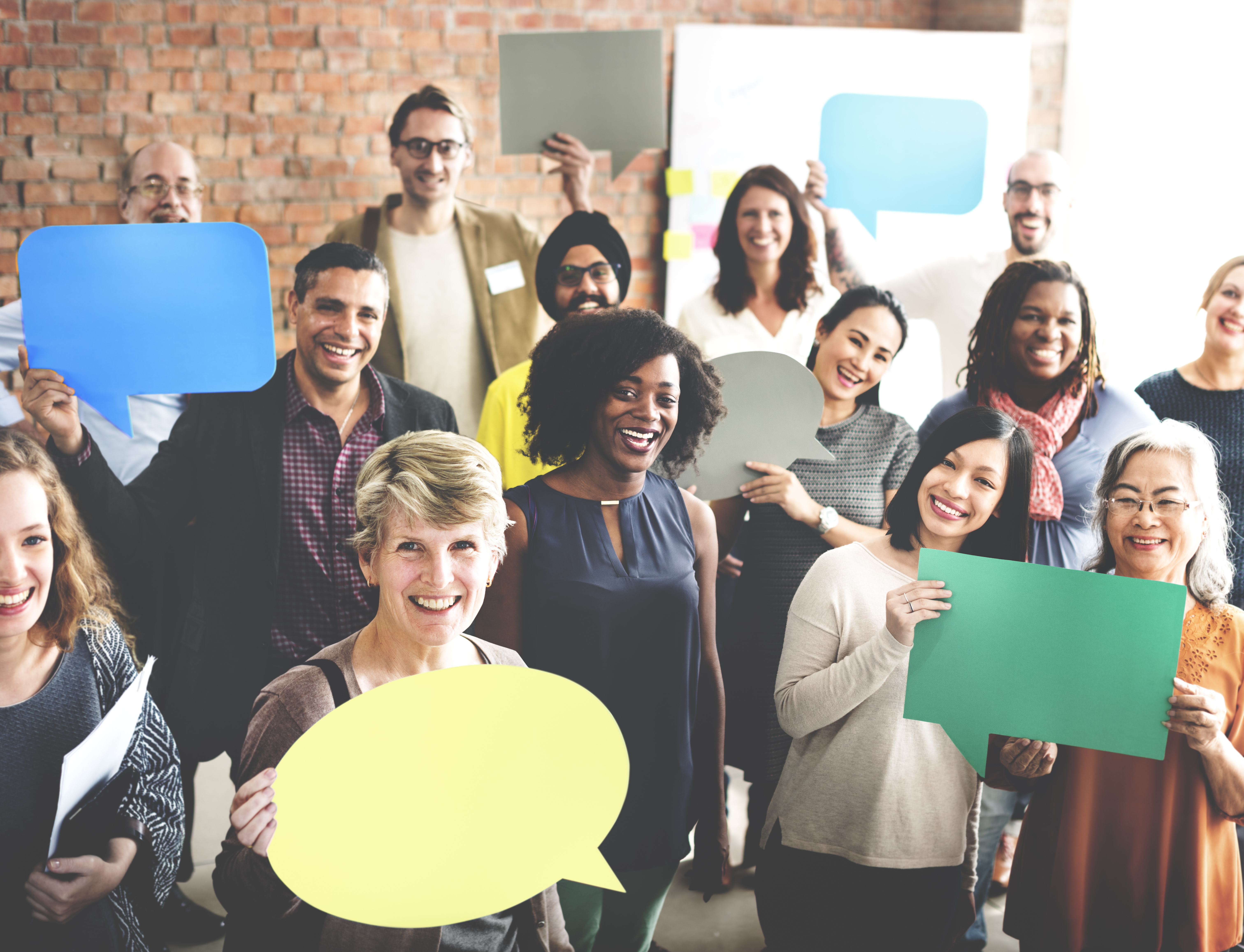 Group of people smiling holding conversation bubble signs