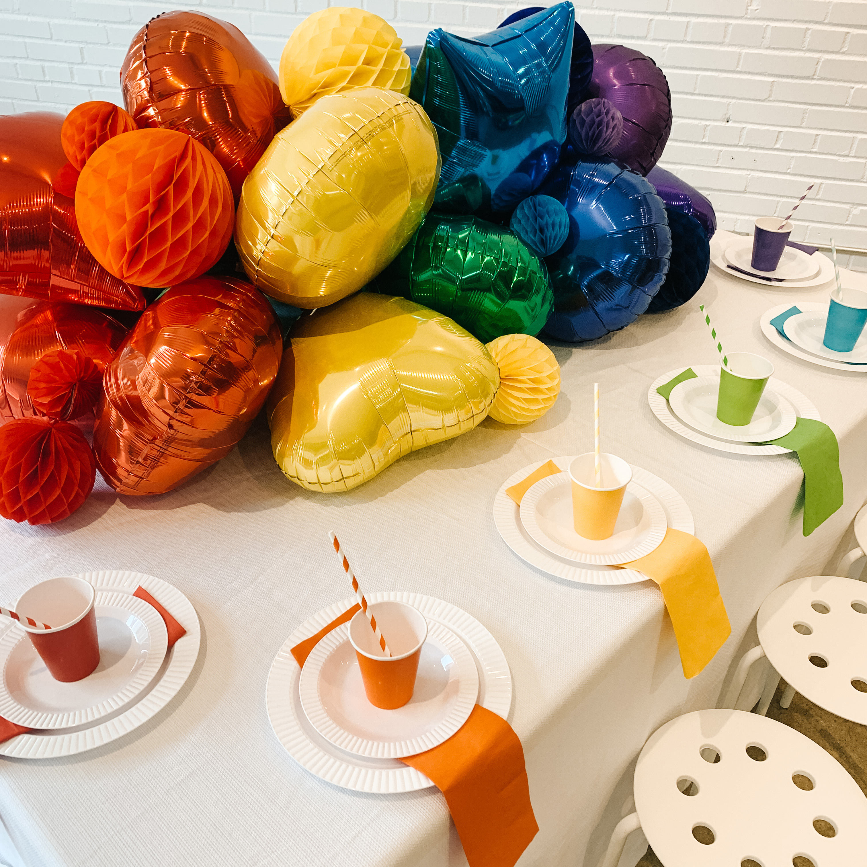 Rainbow balloons, colorful cups and napkins with white plates