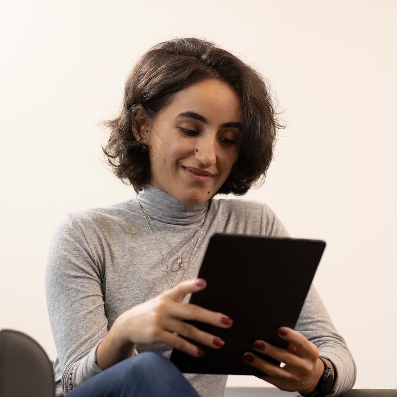 A person is looking at a tablet computer while smiling. 	