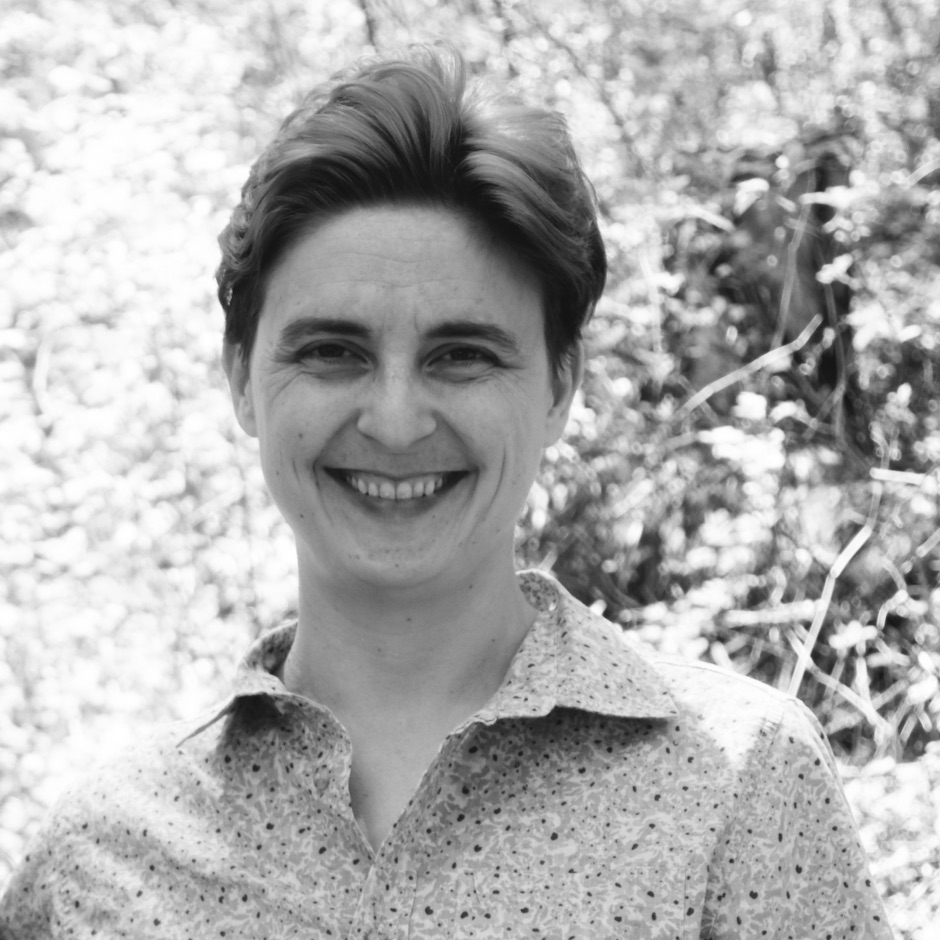 black and white photo of a smiling, short-haired, white person in a floral shirt