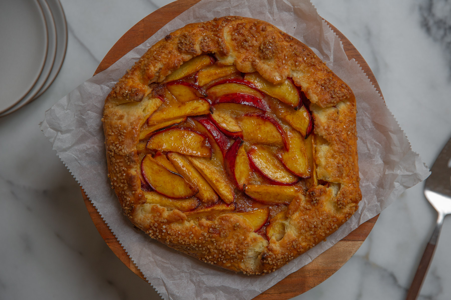 Gluten free peach and almond galette on a pie stand.