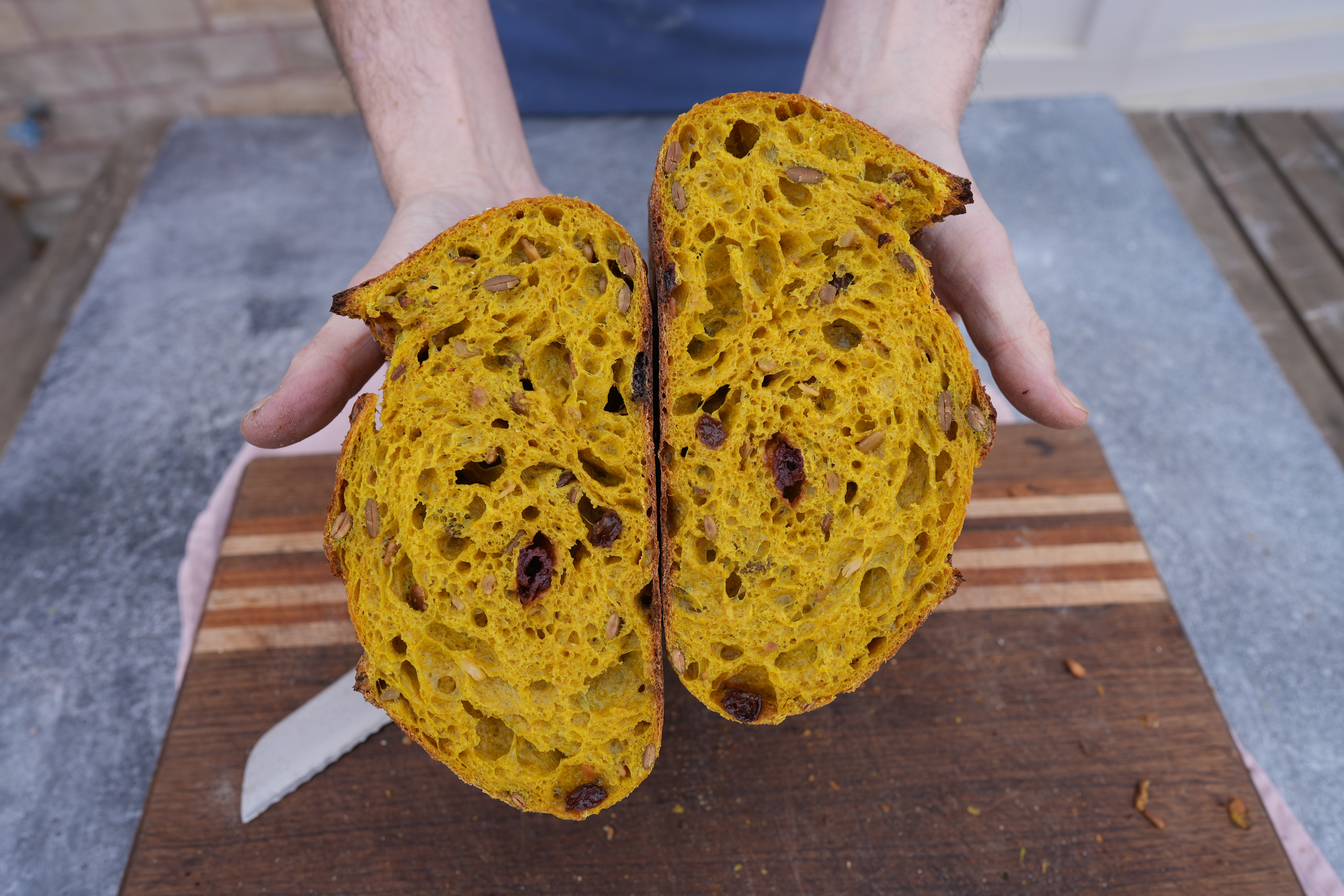 A loaf of turmeric sourdough cut in half showing an open crumb. 