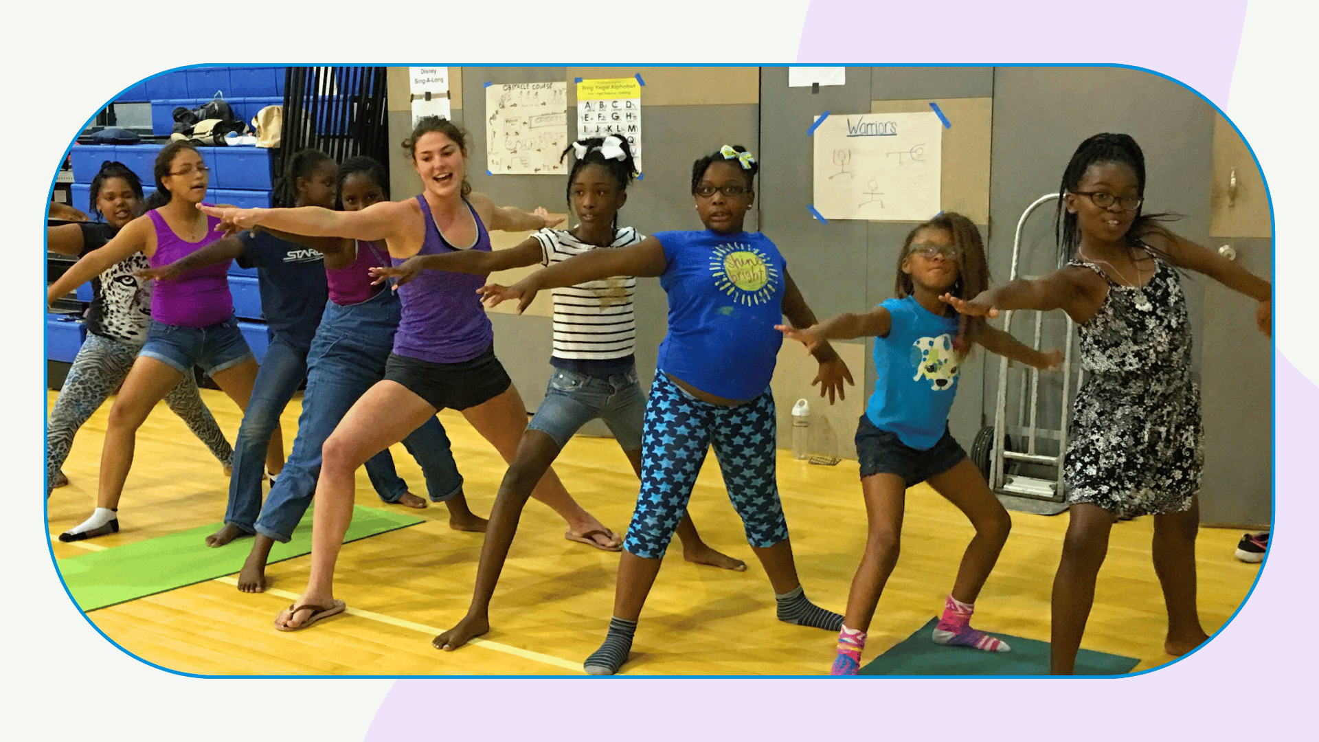 A row of youth do warrior 2 pose with the teacher standing in the middle of the group