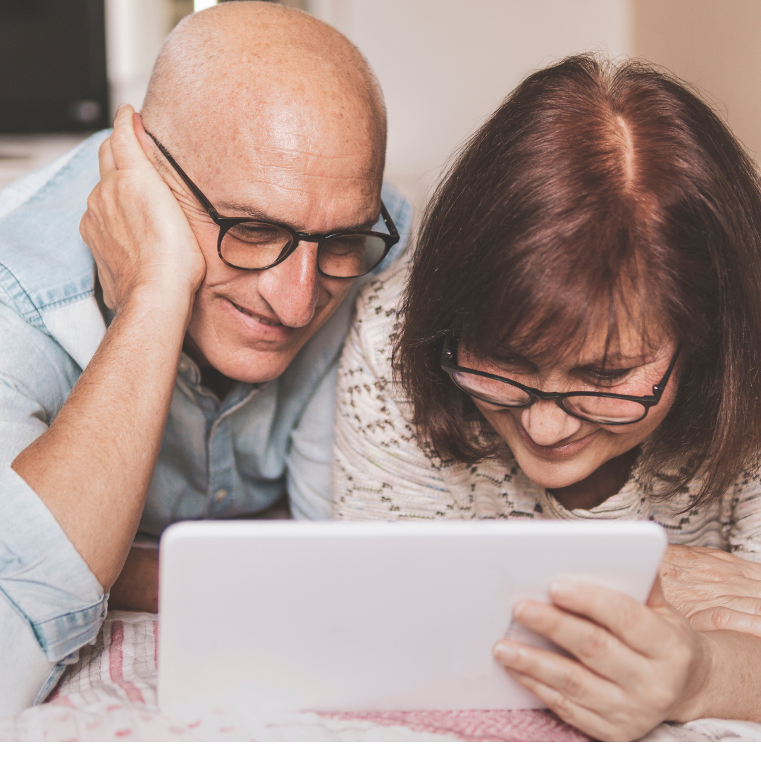 Happy middle-aged couple looking at computer screen smiling