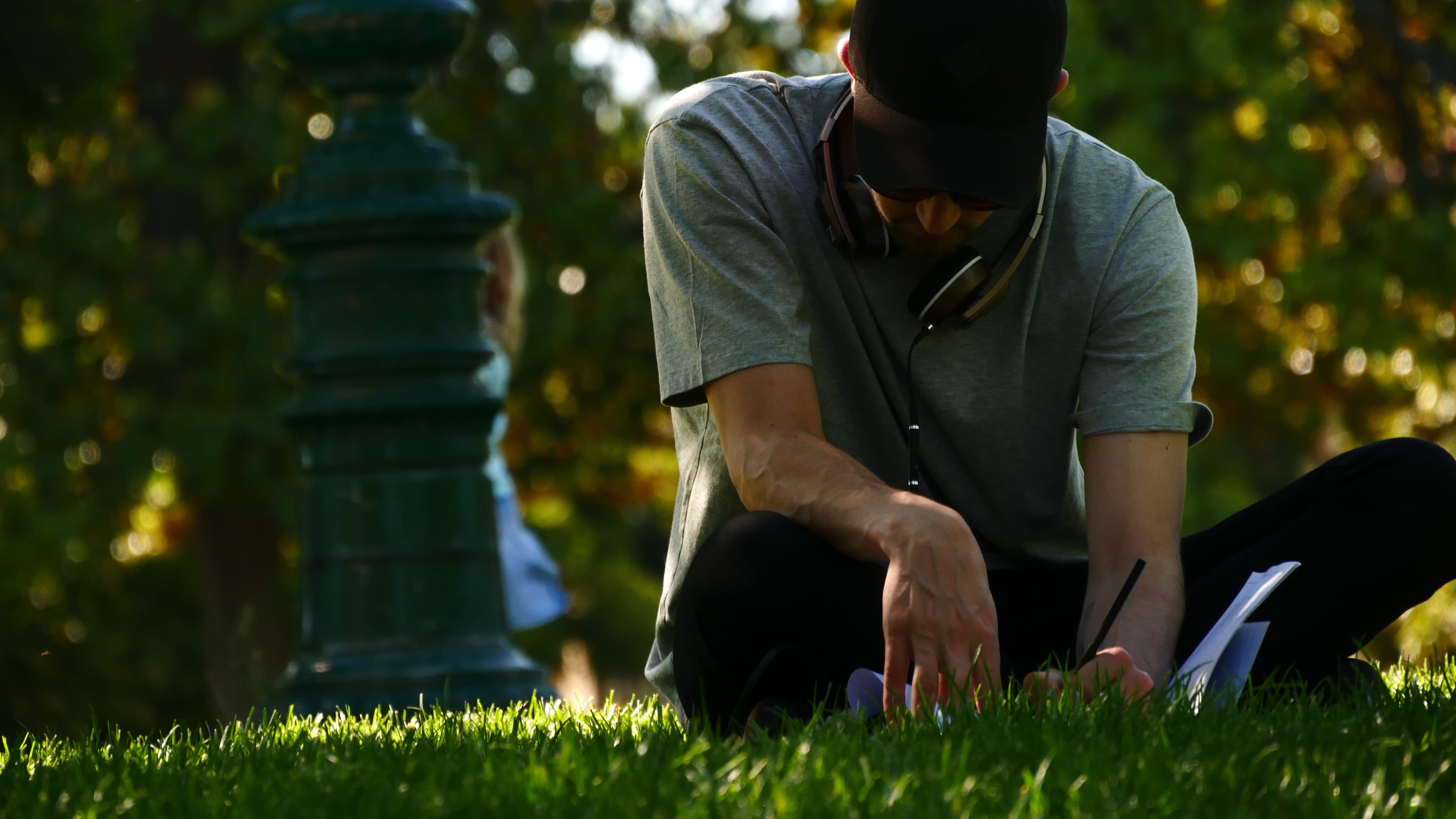 Someone is sitting on the grass and jotting down notes on paper.