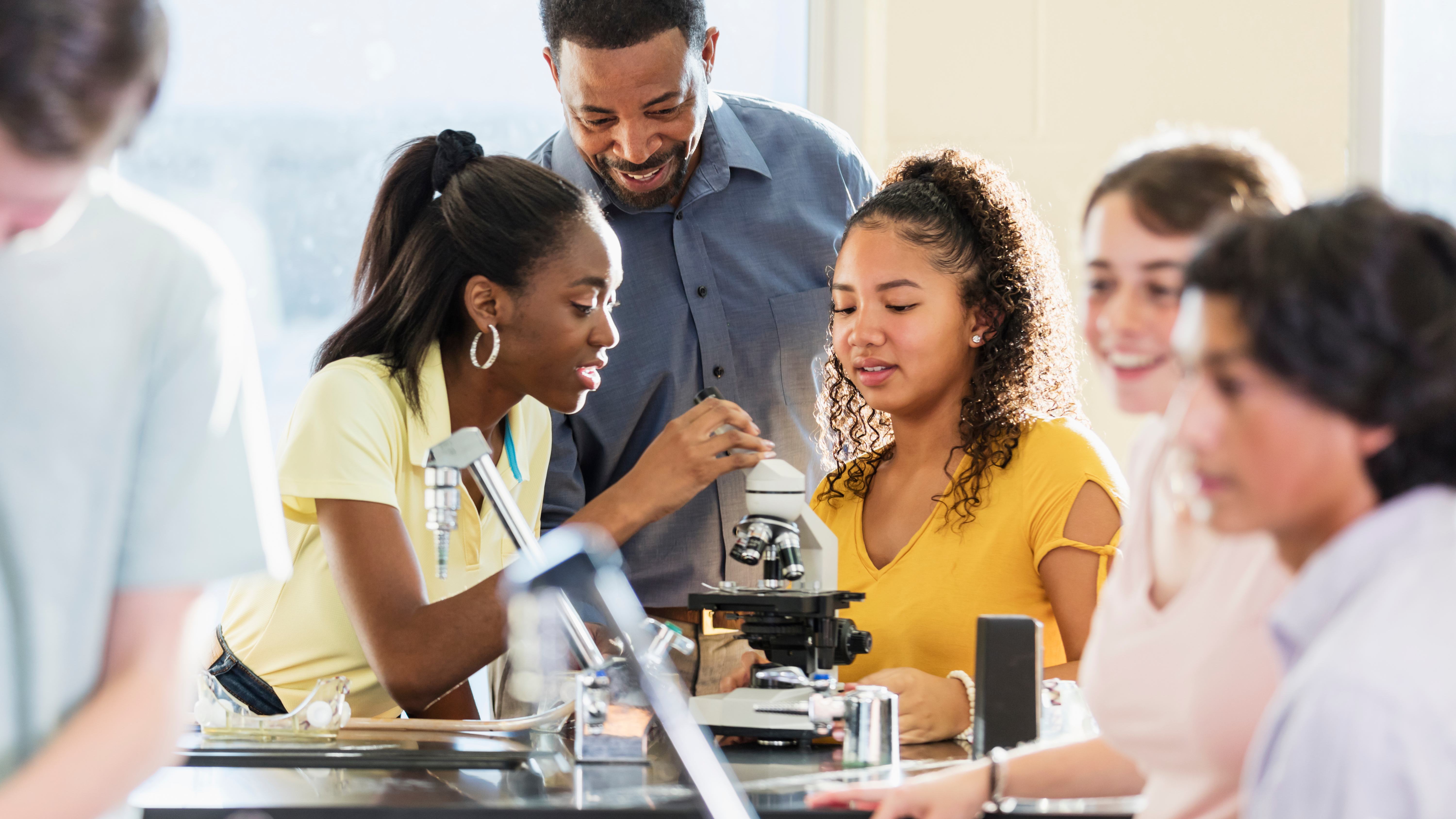 students and teacher using microscope