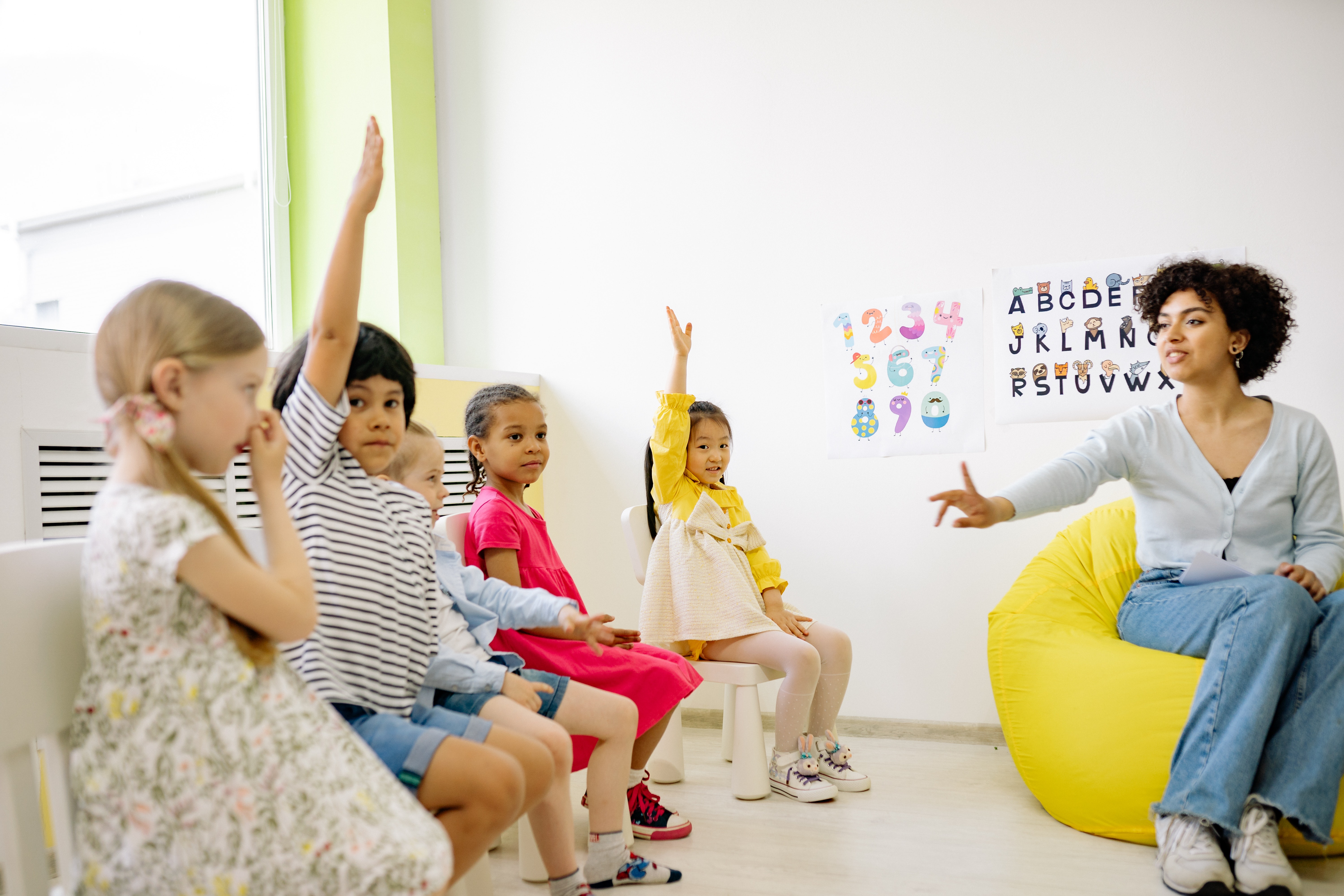 teacher sitting with students with raised hands