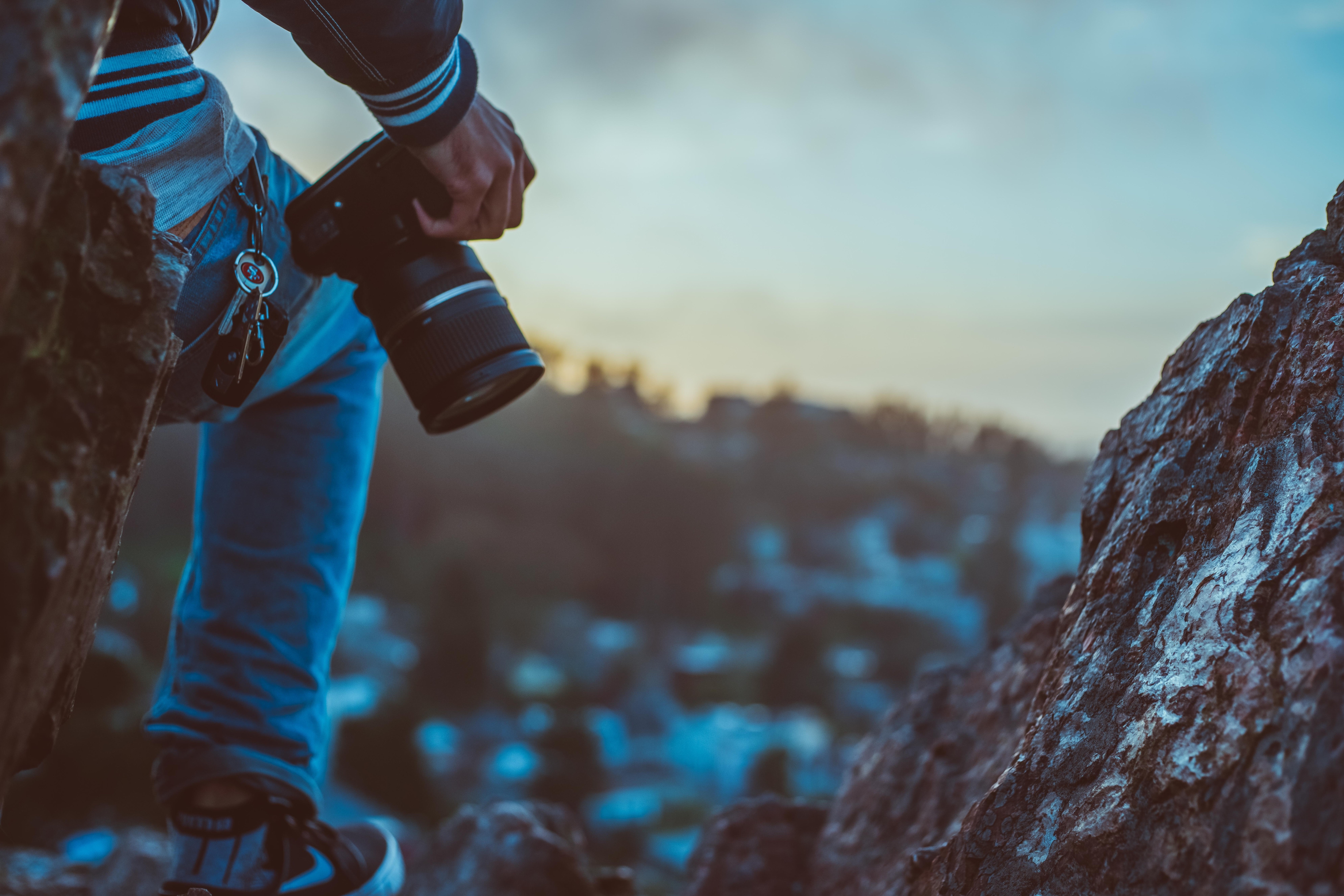 Photographer holding camera and standing next to a rock