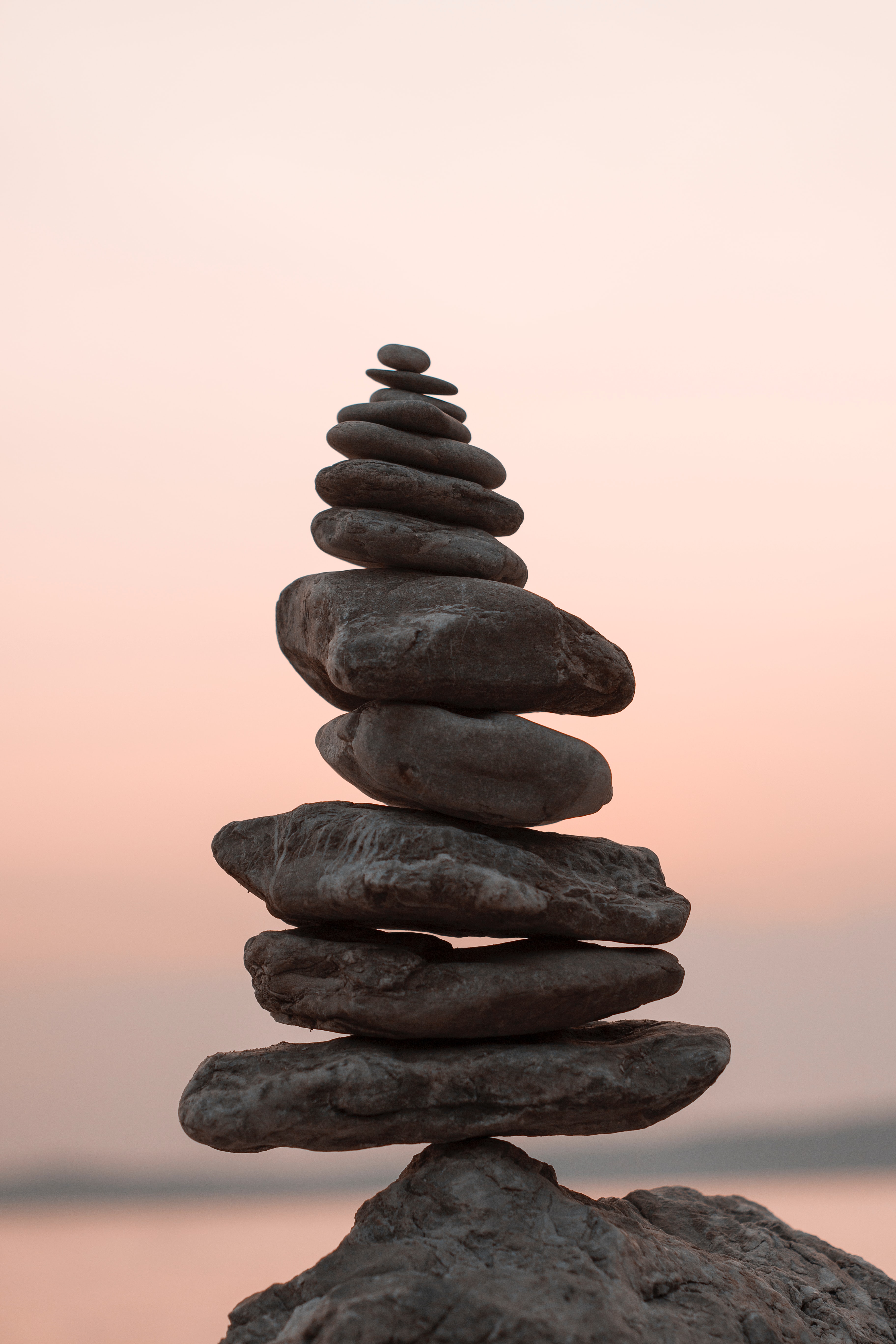 Stacked dark rocks, or cairn, against a sunset background