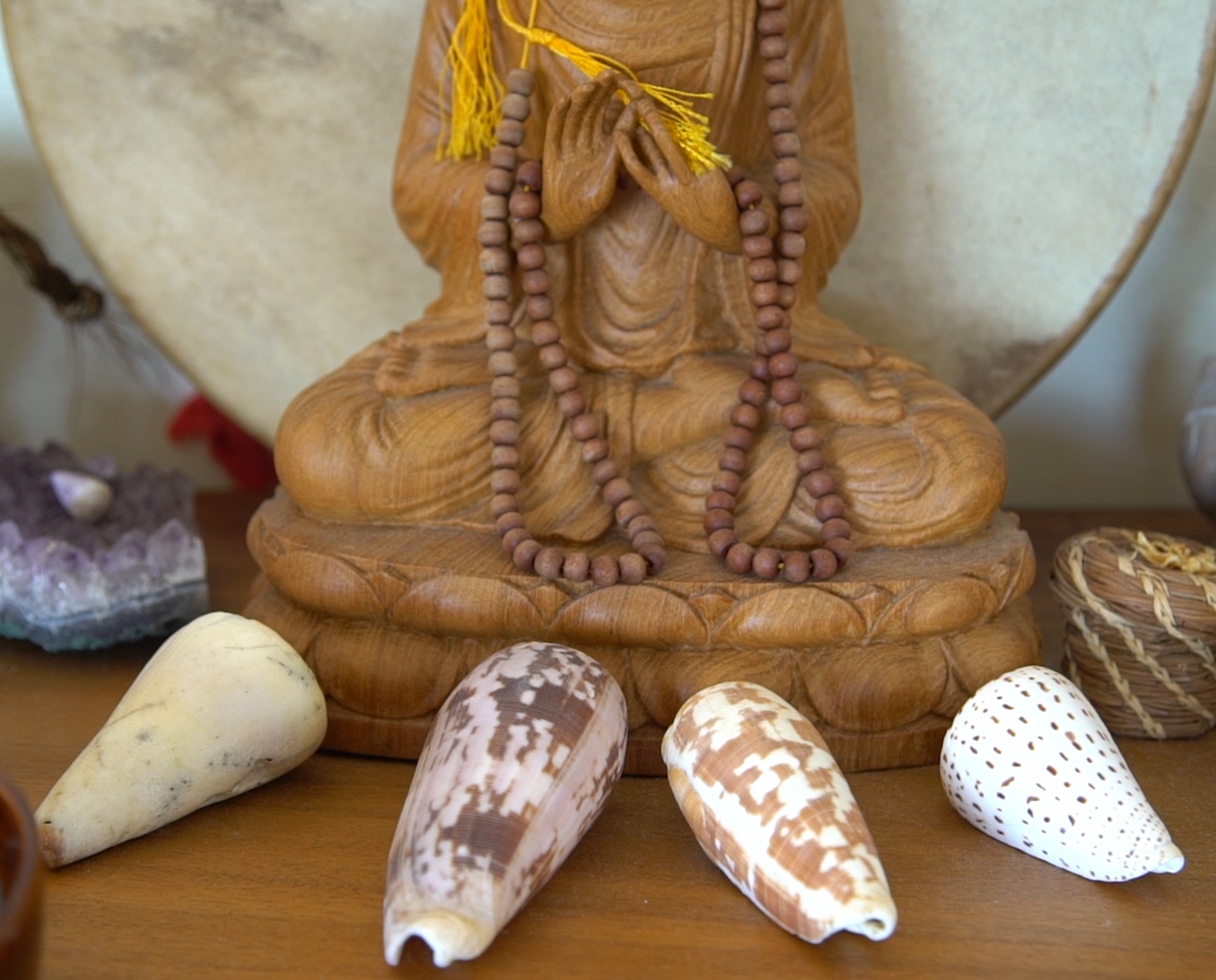 A Buddha statue surrounded by shells from a Hawaiian beach