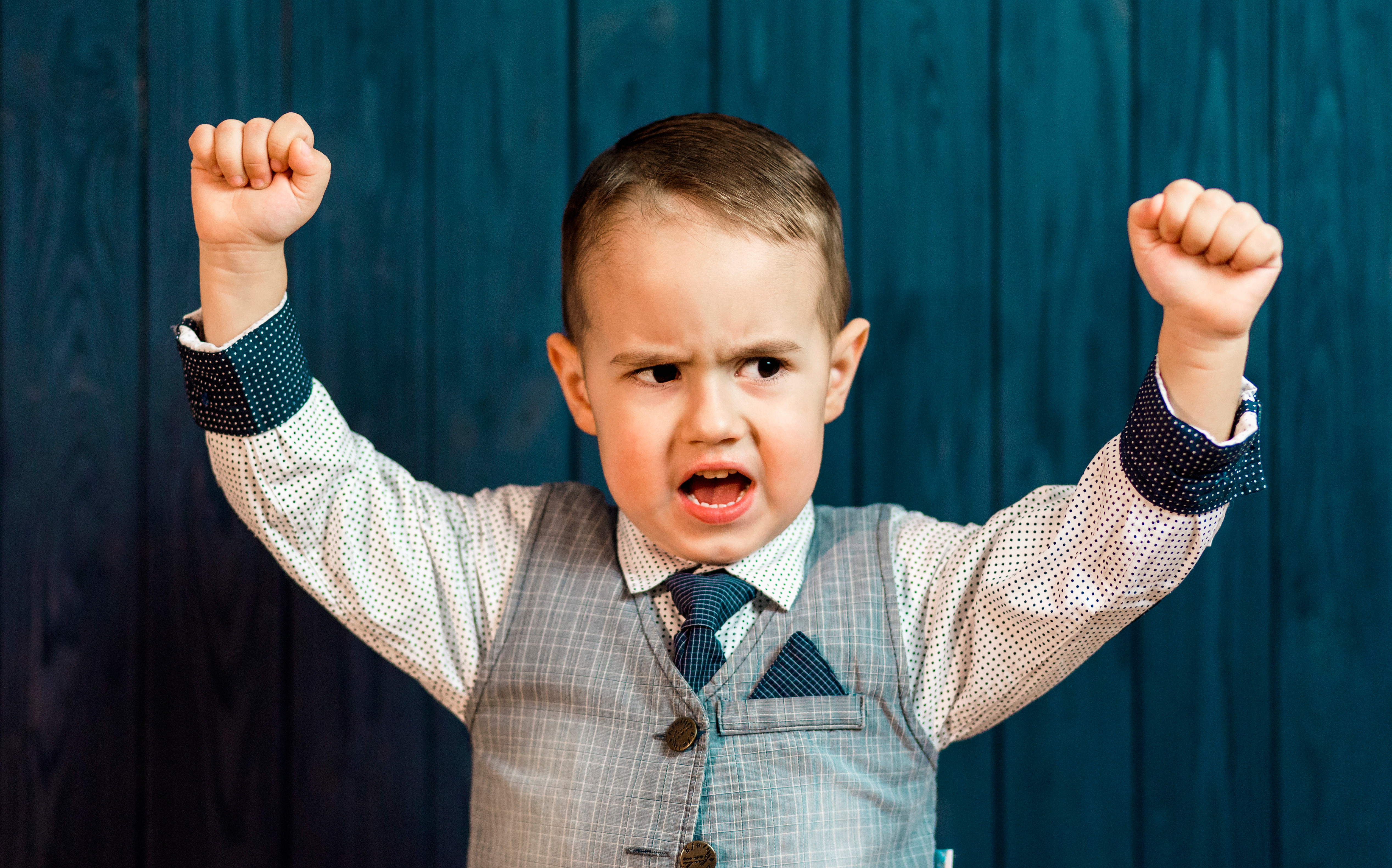 young child with arms in the air and stressed look on face