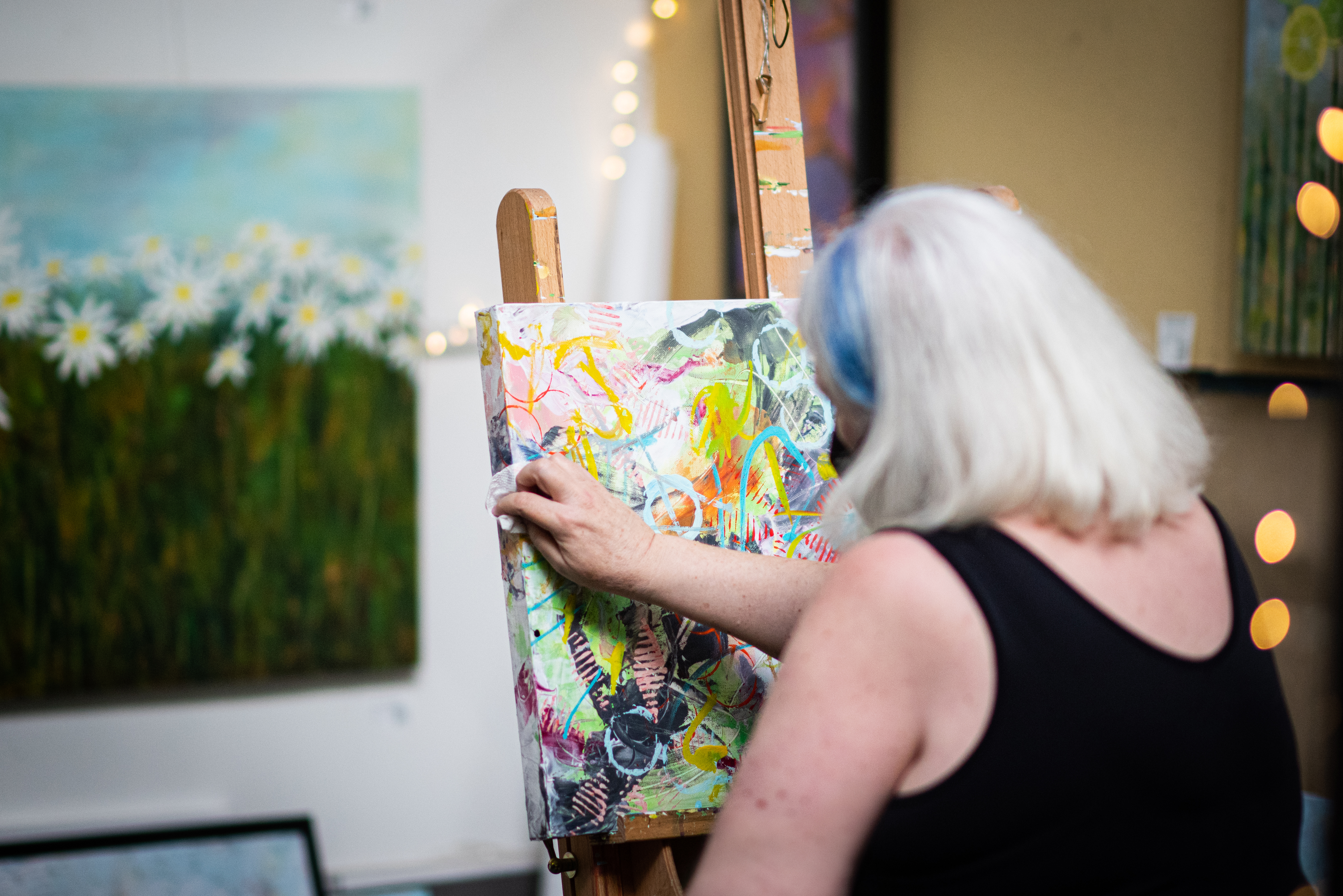 Female artist wiping her canvas with a paper towel.