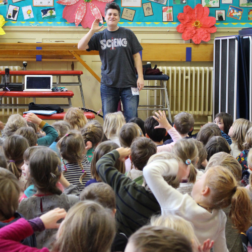 image shows Al Start from Go Kid Music leading a singing assembly with children