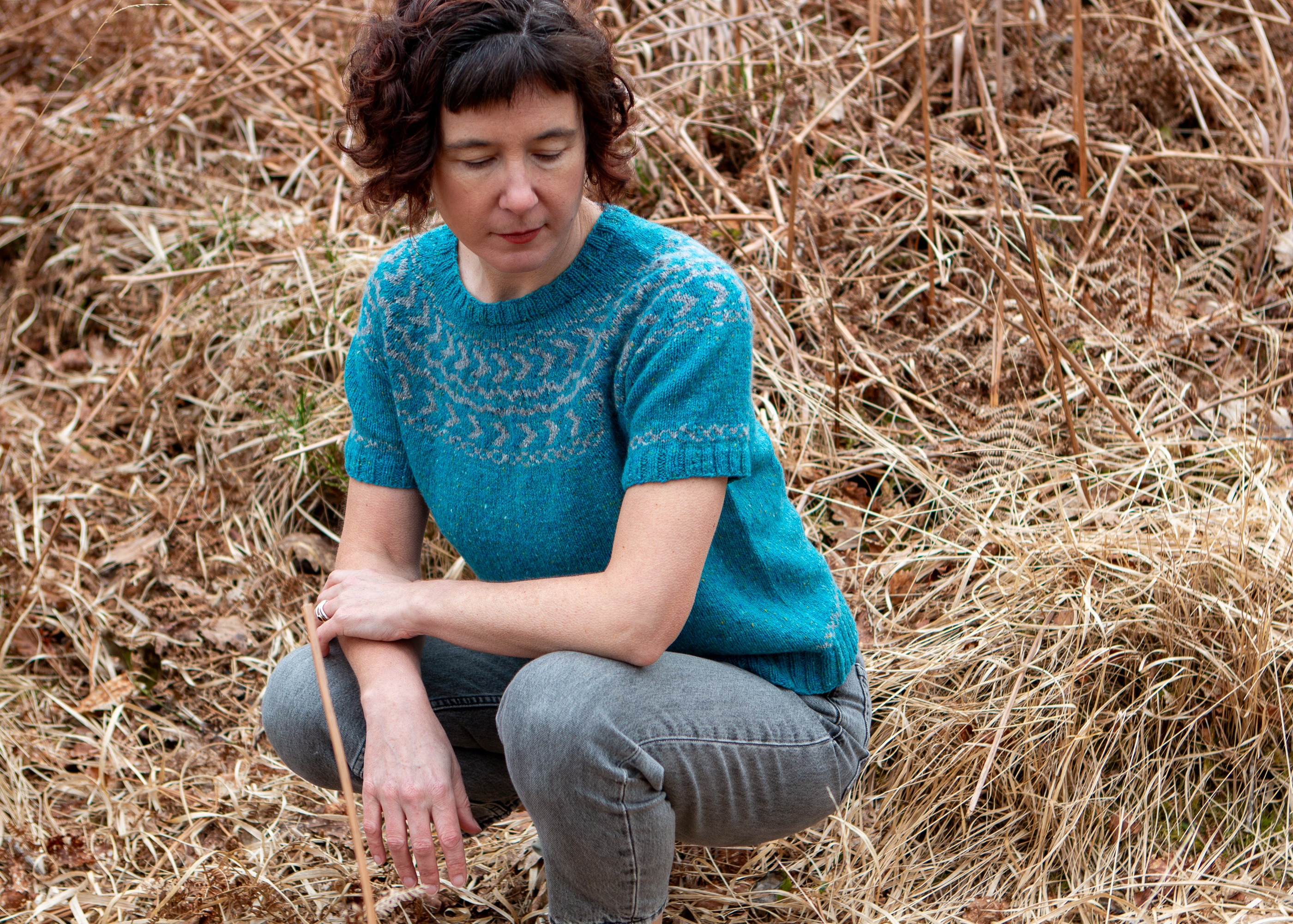 Carol Feller wearing the short sleeved Daingean Sweater crouched down .