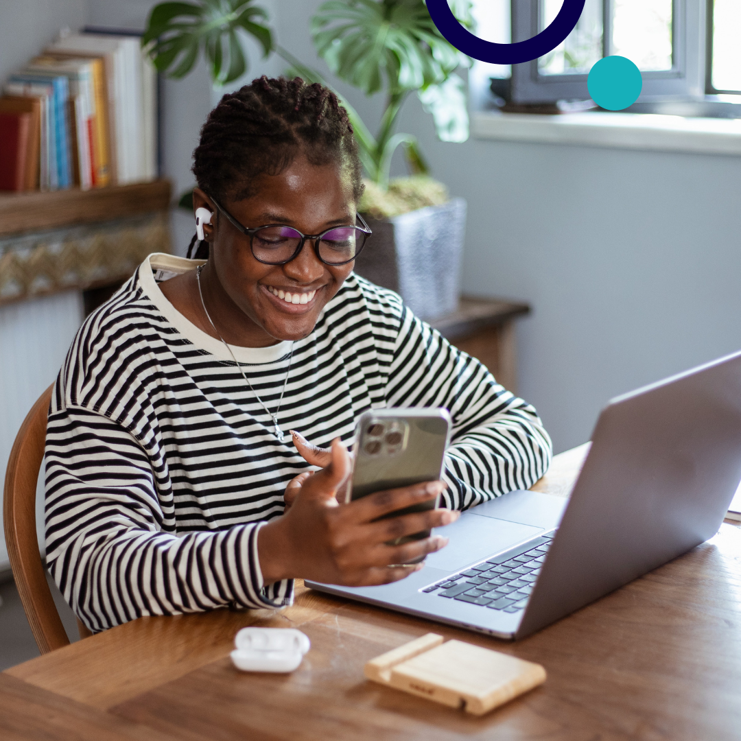 Woman wearing earbuds working on a laptop and computer.