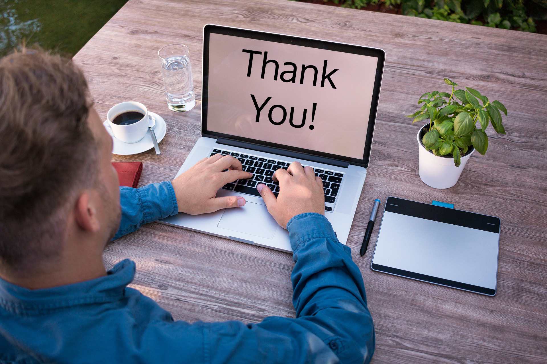 Man sitting at a laptop with a screen that reads thank you