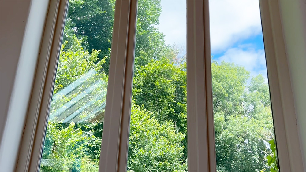 A window with trees, clouds, and a blue sky