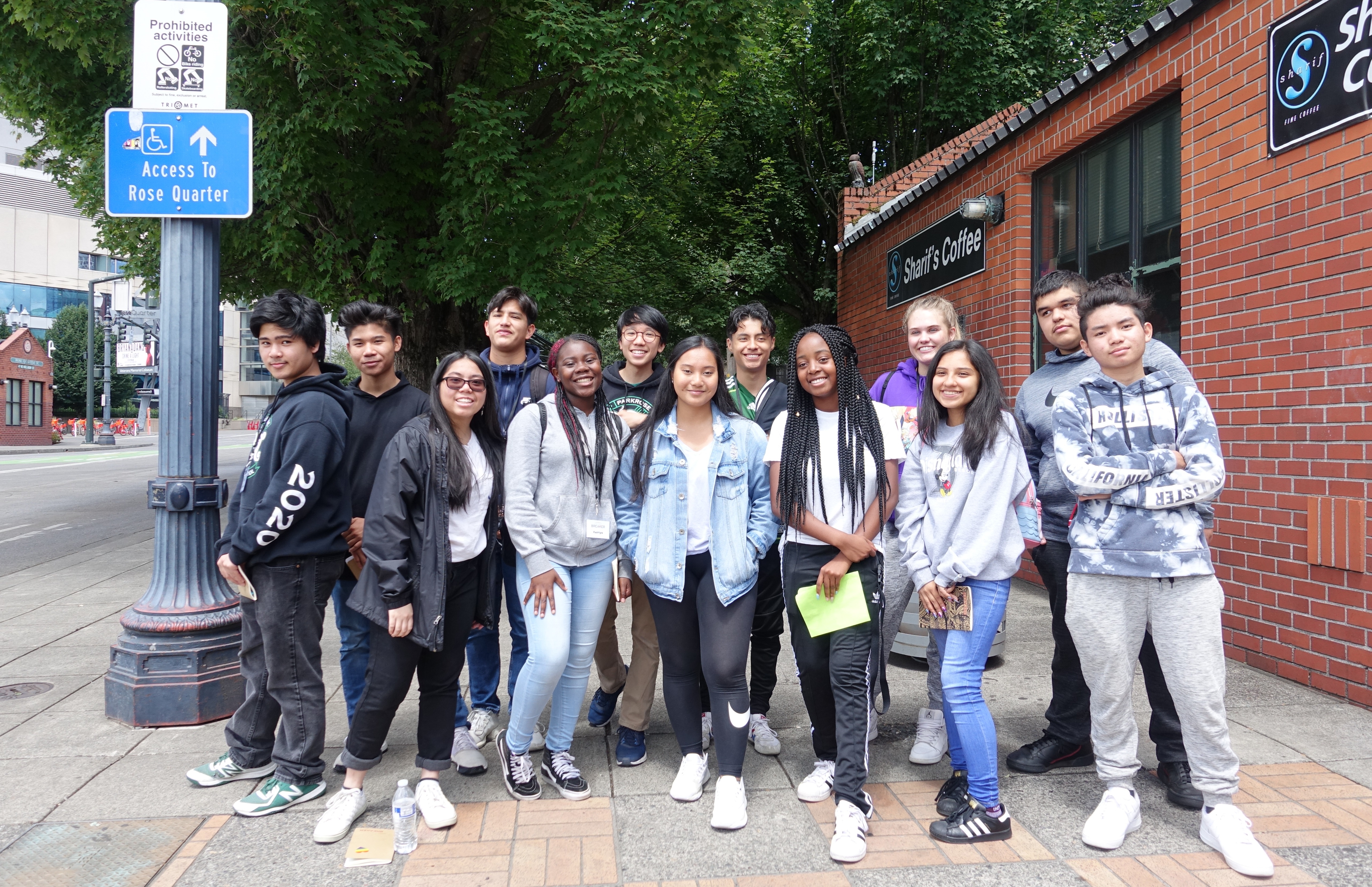 A group of smiling students outside on a city street looking delightful. 