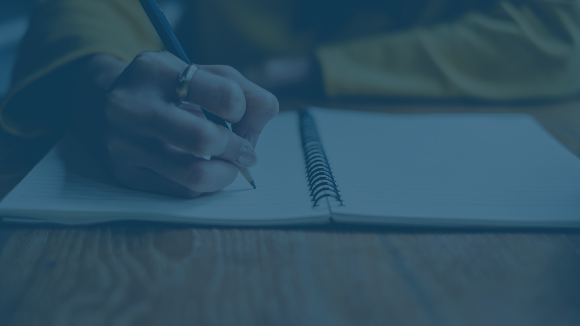 Person writing in a notebook with a pencil