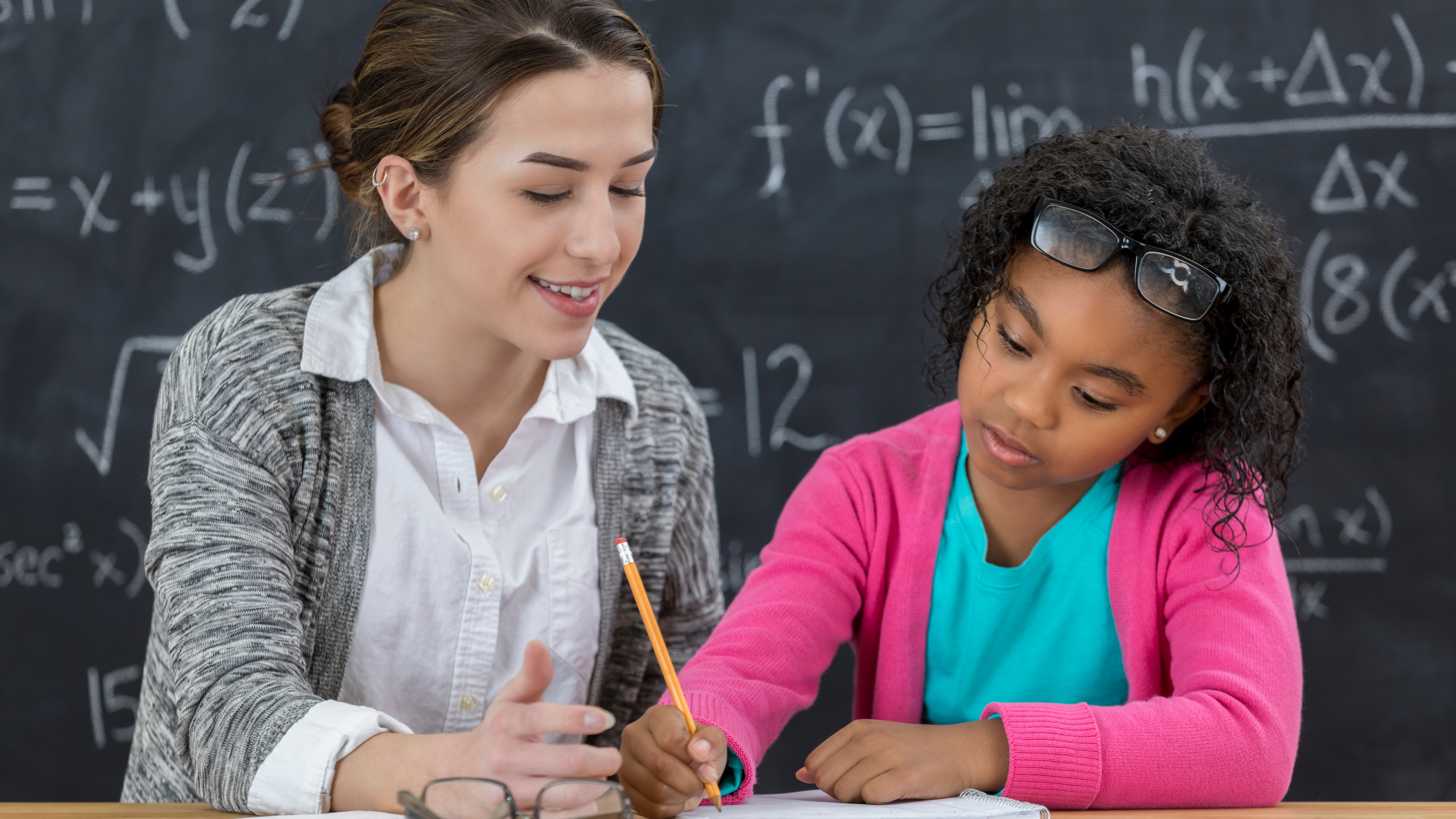 teacher working aside student who is writing