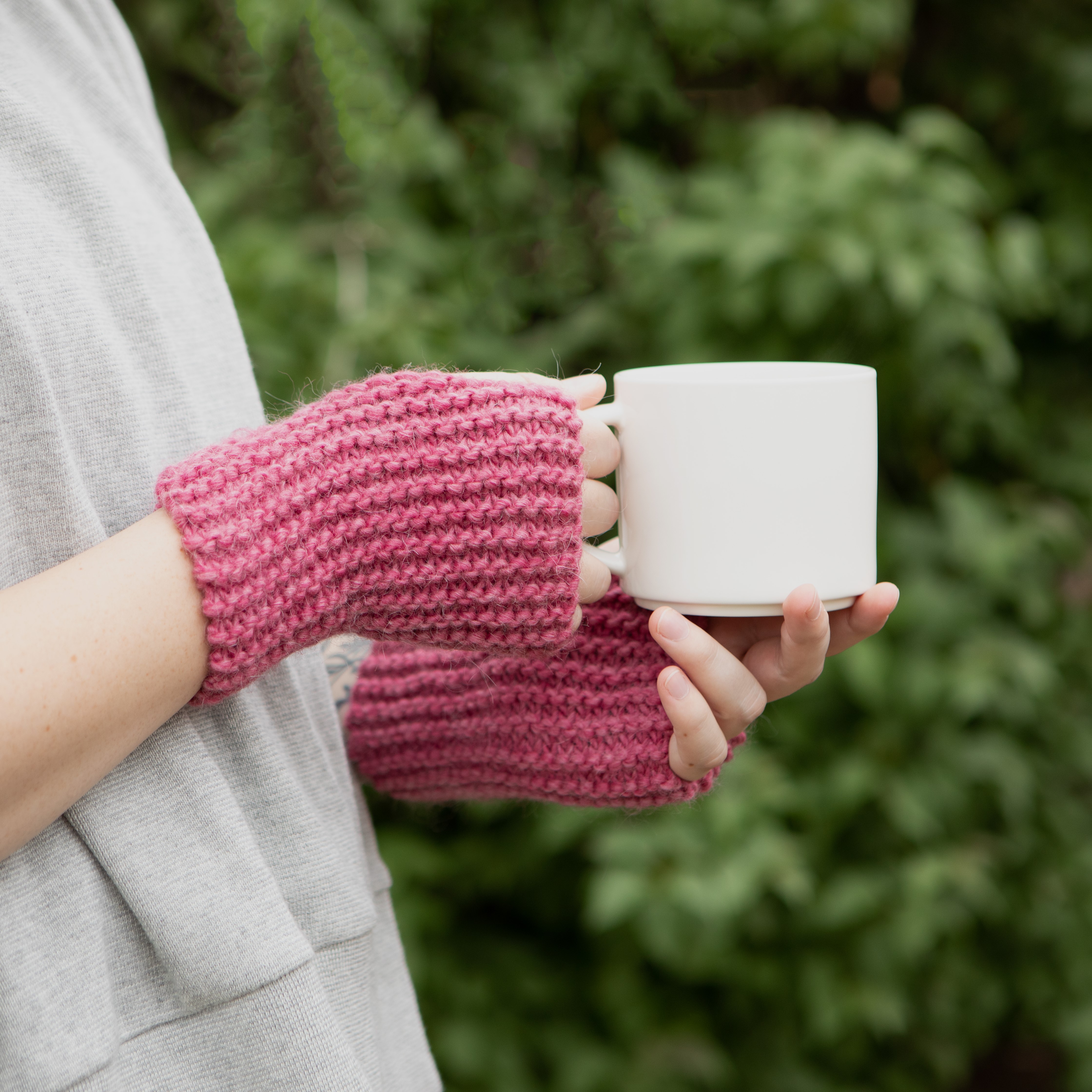 Knit wrist warmers holding a coffee cup 