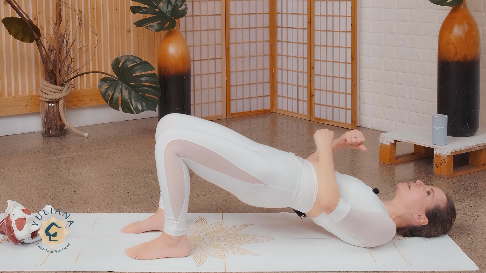 woman in a workout yoga studio doing yoga and holding a glut bridge