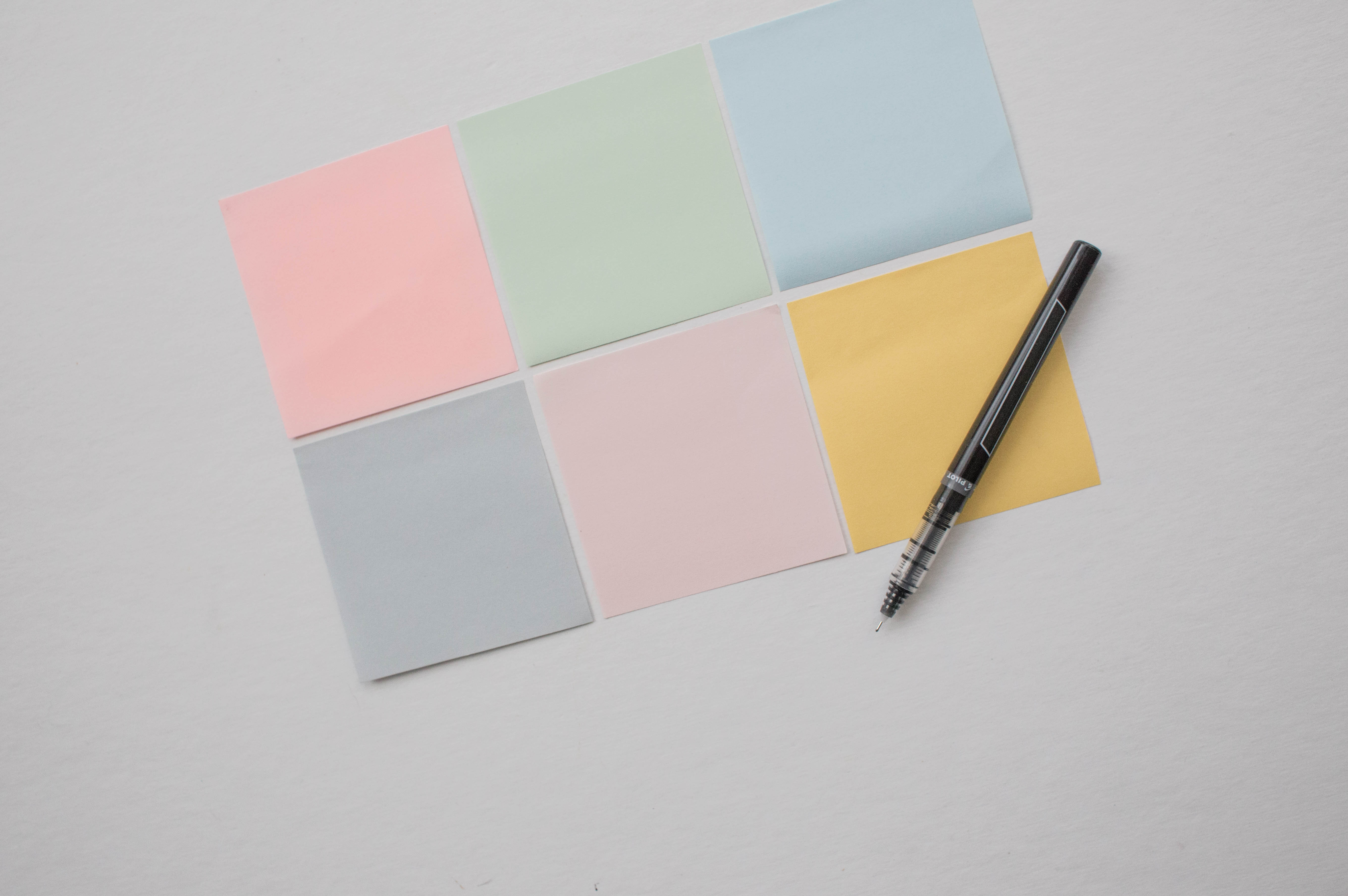 Six post-it sticky notes with a ballpoint pen on a gray background - photo credit Death to the Stock Photo, free to use in commercial contexts