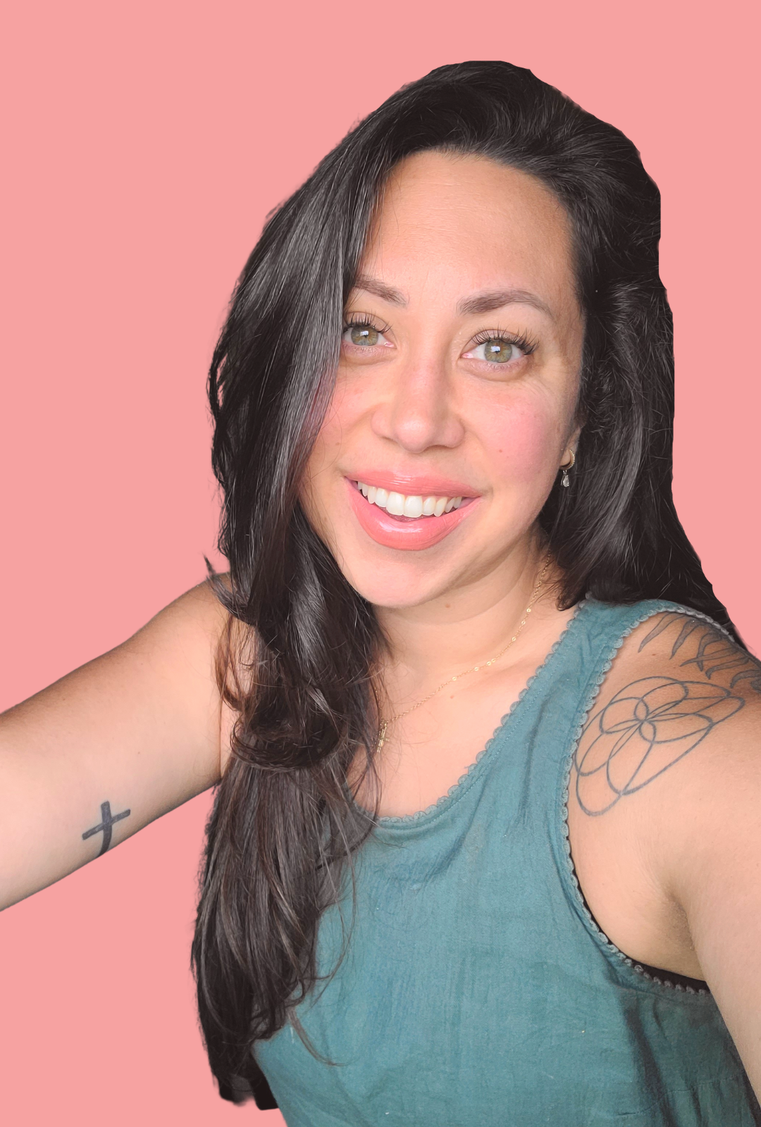 A white woman with long brunette hair on a salmon pink background. Dierdre has visible tattoos like a solid black cross on her left upper arm, as well as a seed of life and palm leaf on her rights shoulder