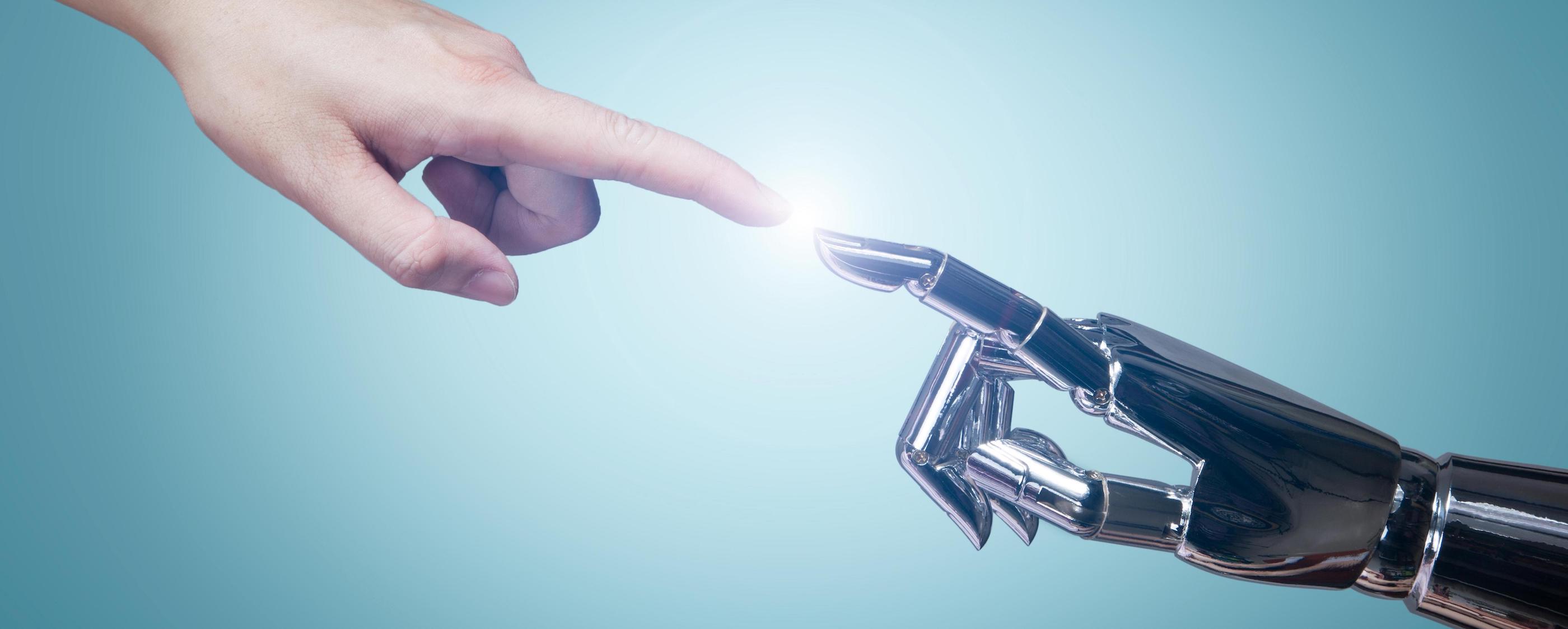 Finger of a human touching the finger of a robot with a light in between their fingertips