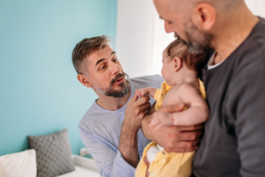 Dads with their baby in process of dressing the little one