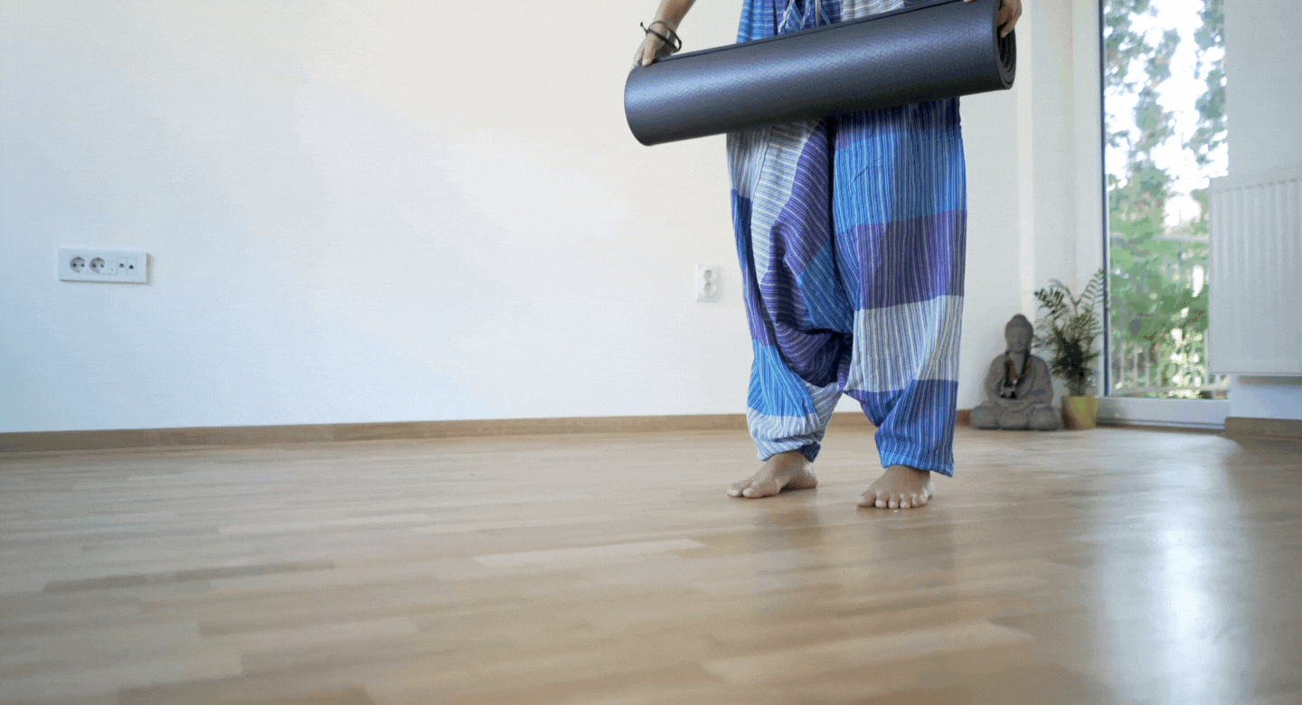 Woman rolling a yoga mat on the floor.