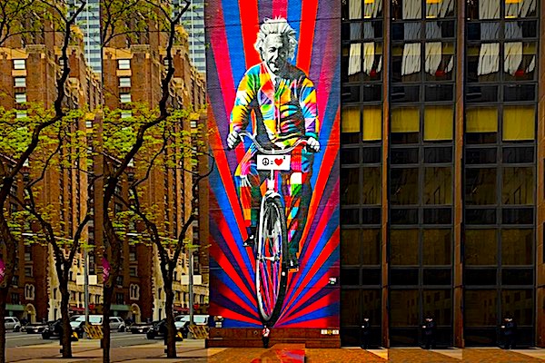 Hanging from the top of a tall building, a very large picture of Einstein riding a bicycle represents the category &#39;Famous People&#39;