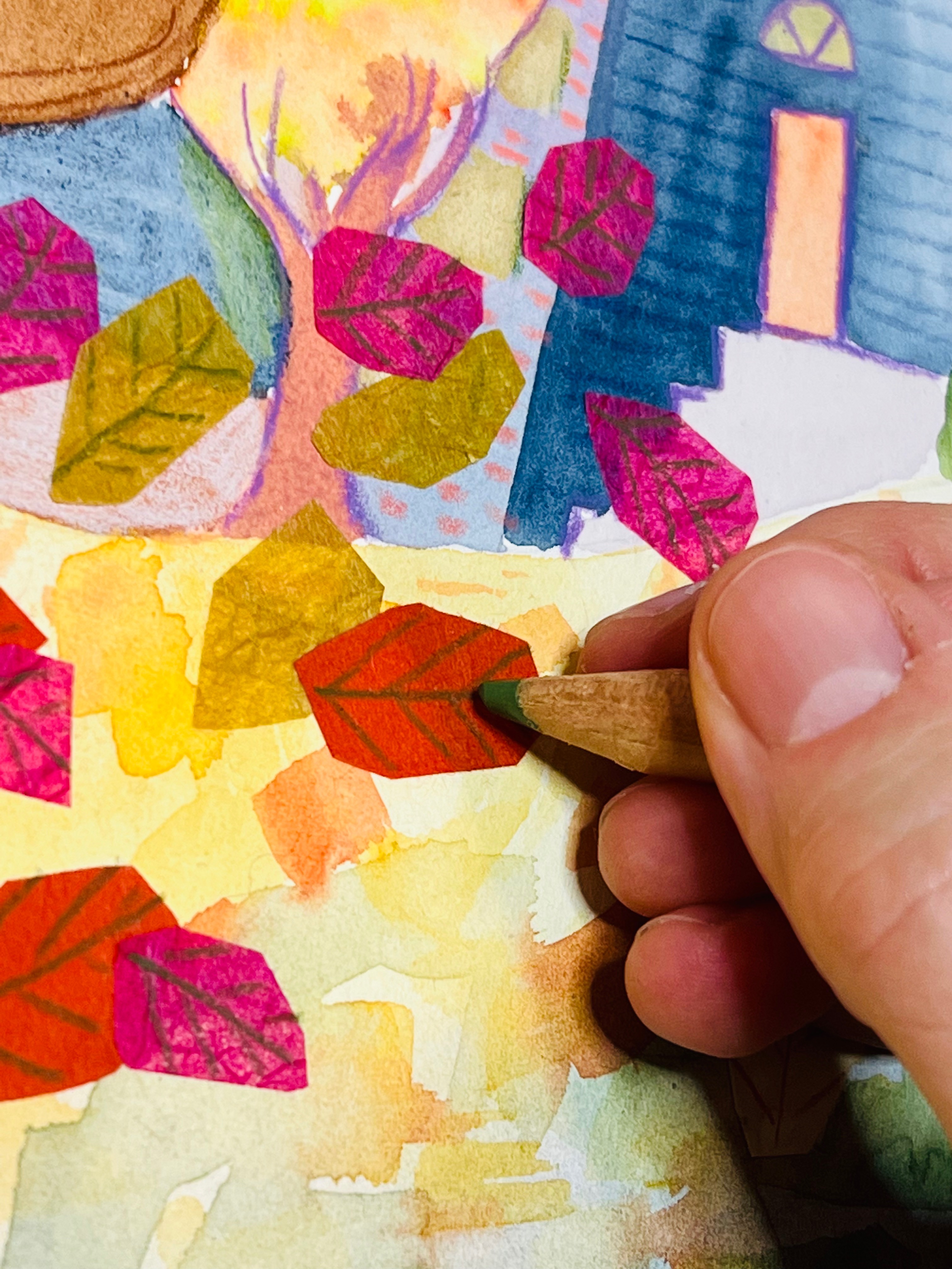 a hand holding a green colored pencil drawing on colorful paper leaves