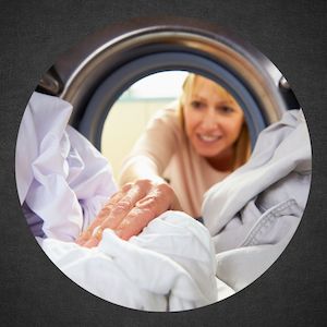 woman reaching into dryer to grab clean clothes