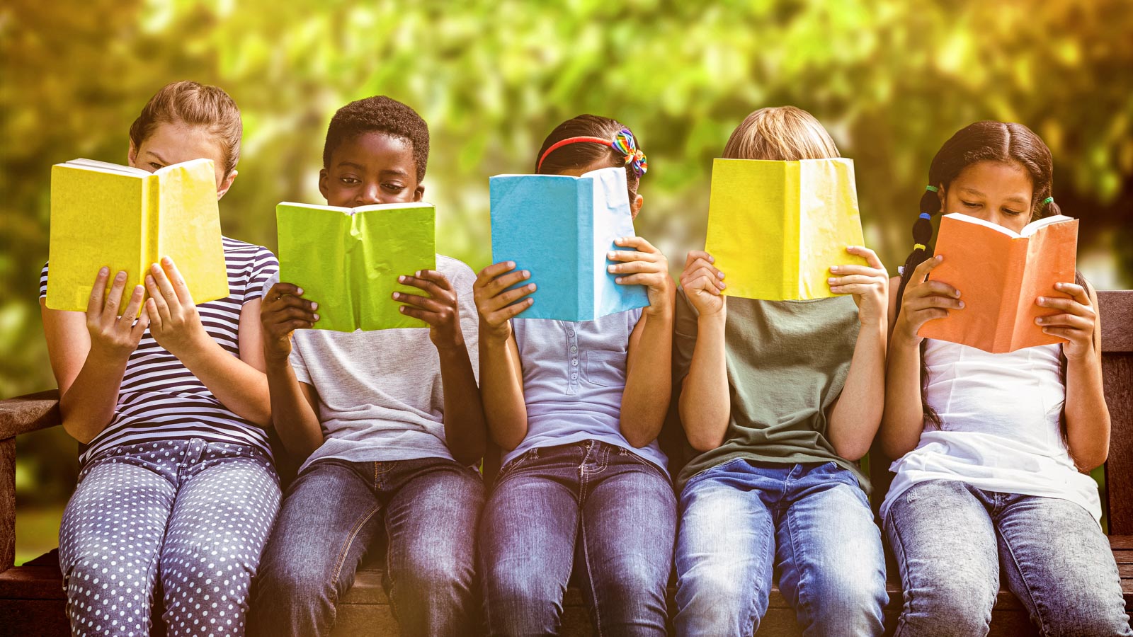 Five children of all races and genders sit outside reading books with colorful covers
